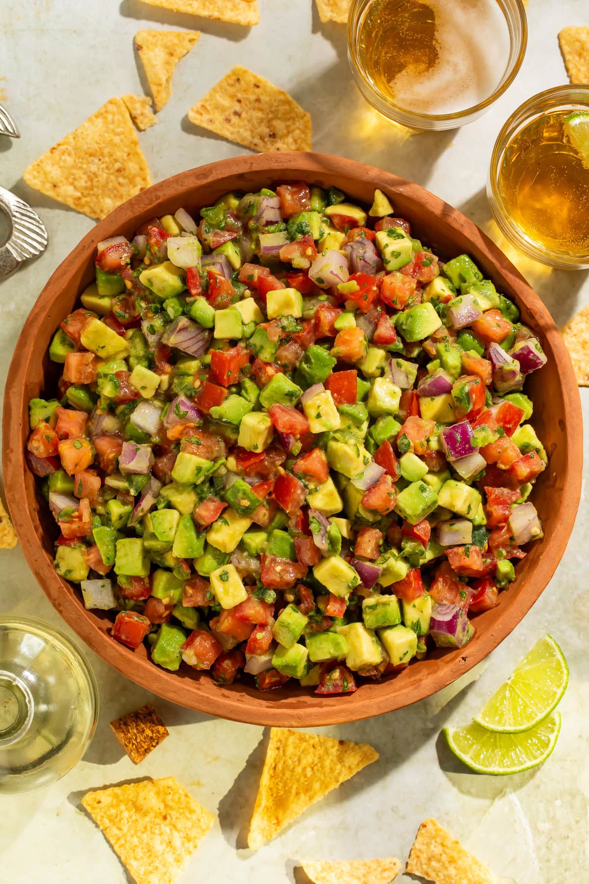 Chunky avocado tomato salsa in a wooden bowl with diced avocados, roma tomatoes, and red onion