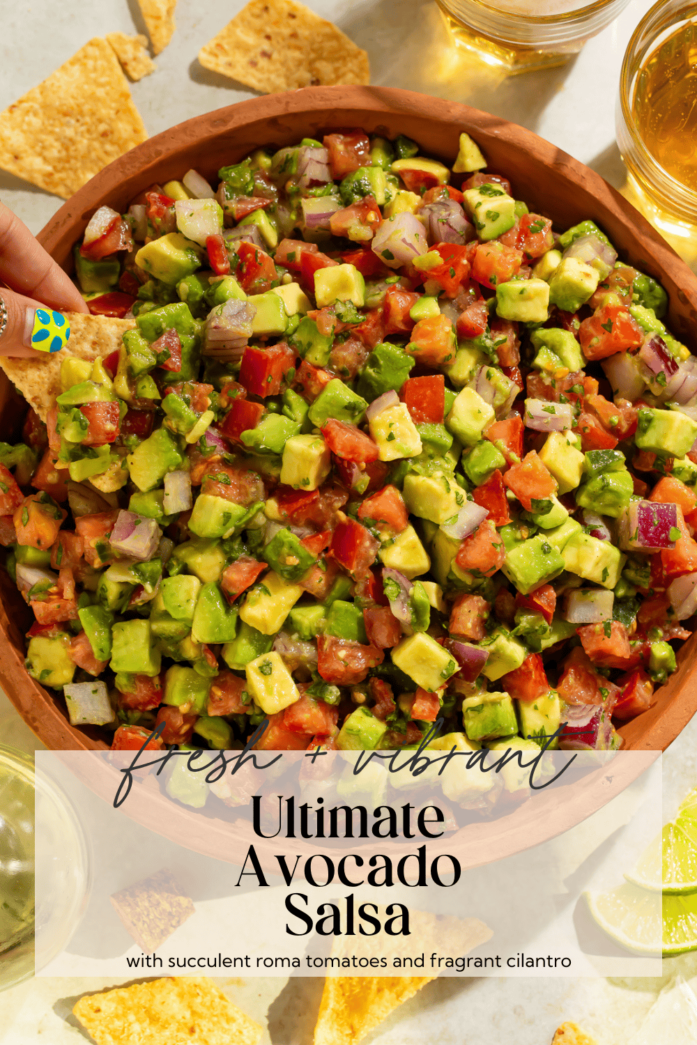 Avocado tomato salsa in wooden bowl with tortilla chips on rustic table setting