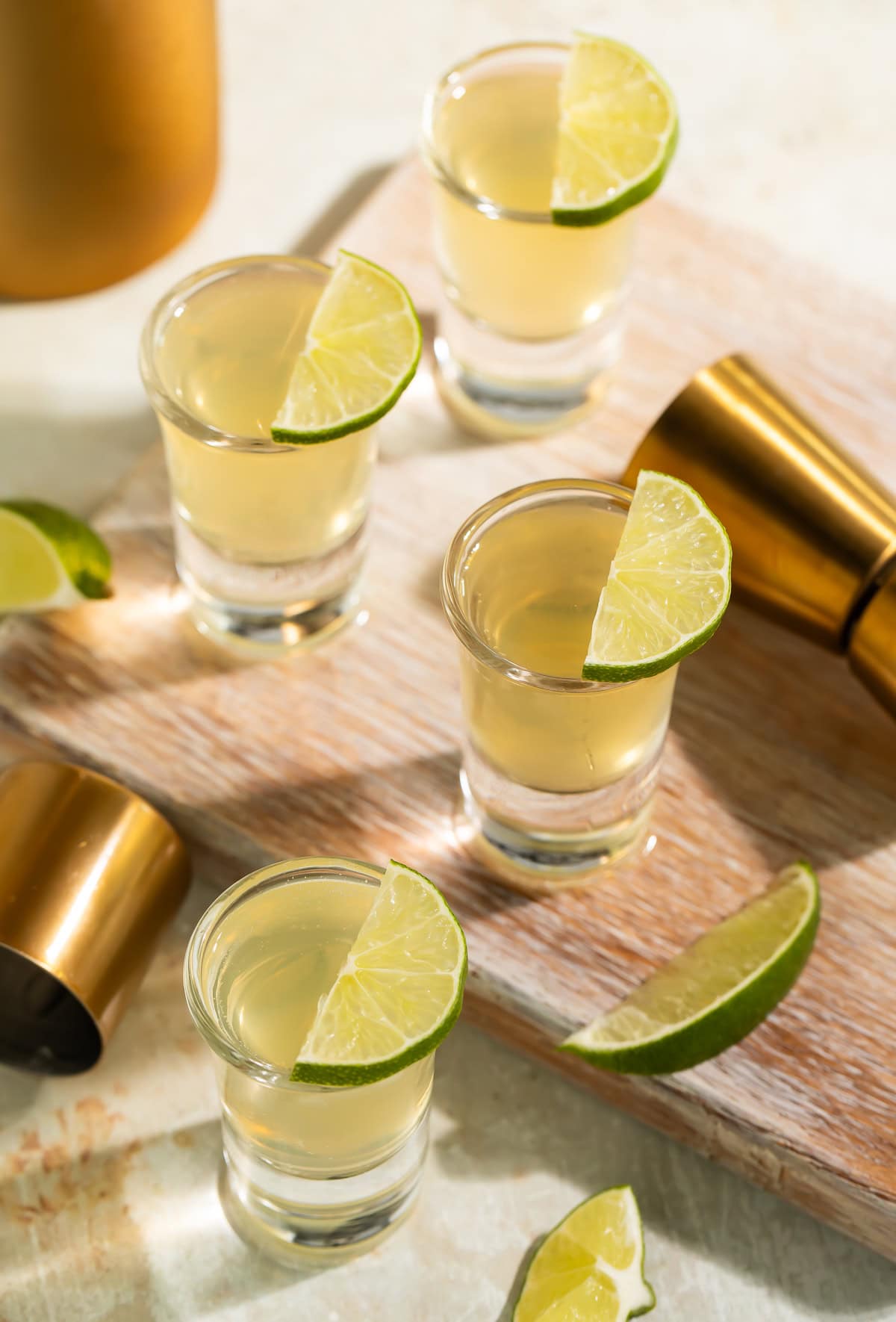 Multiple green tea shots being poured from cocktail shaker into shot glasses at party