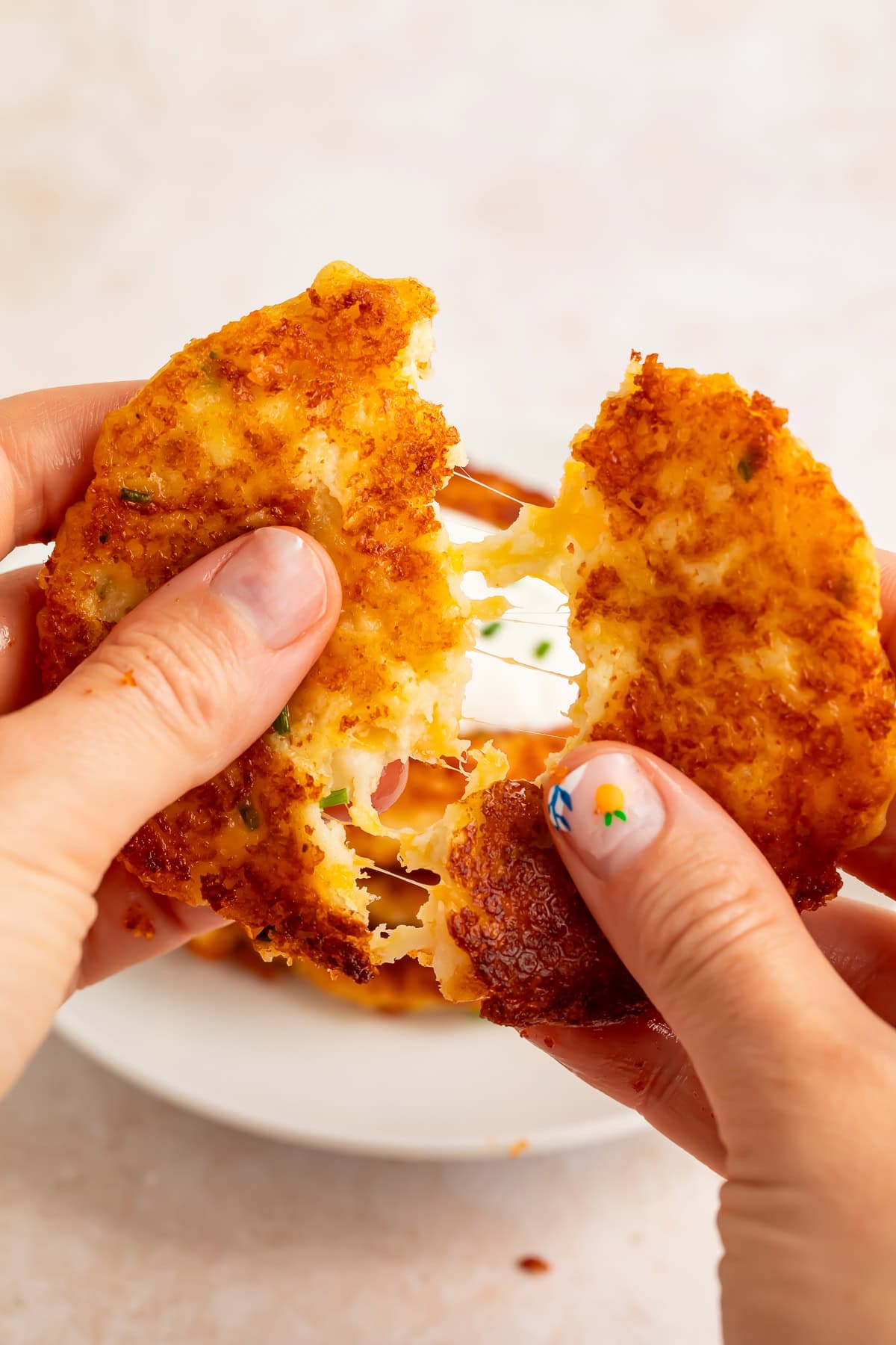 Hands pulling apart crispy potato pancake showing fluffy creamy interior texture