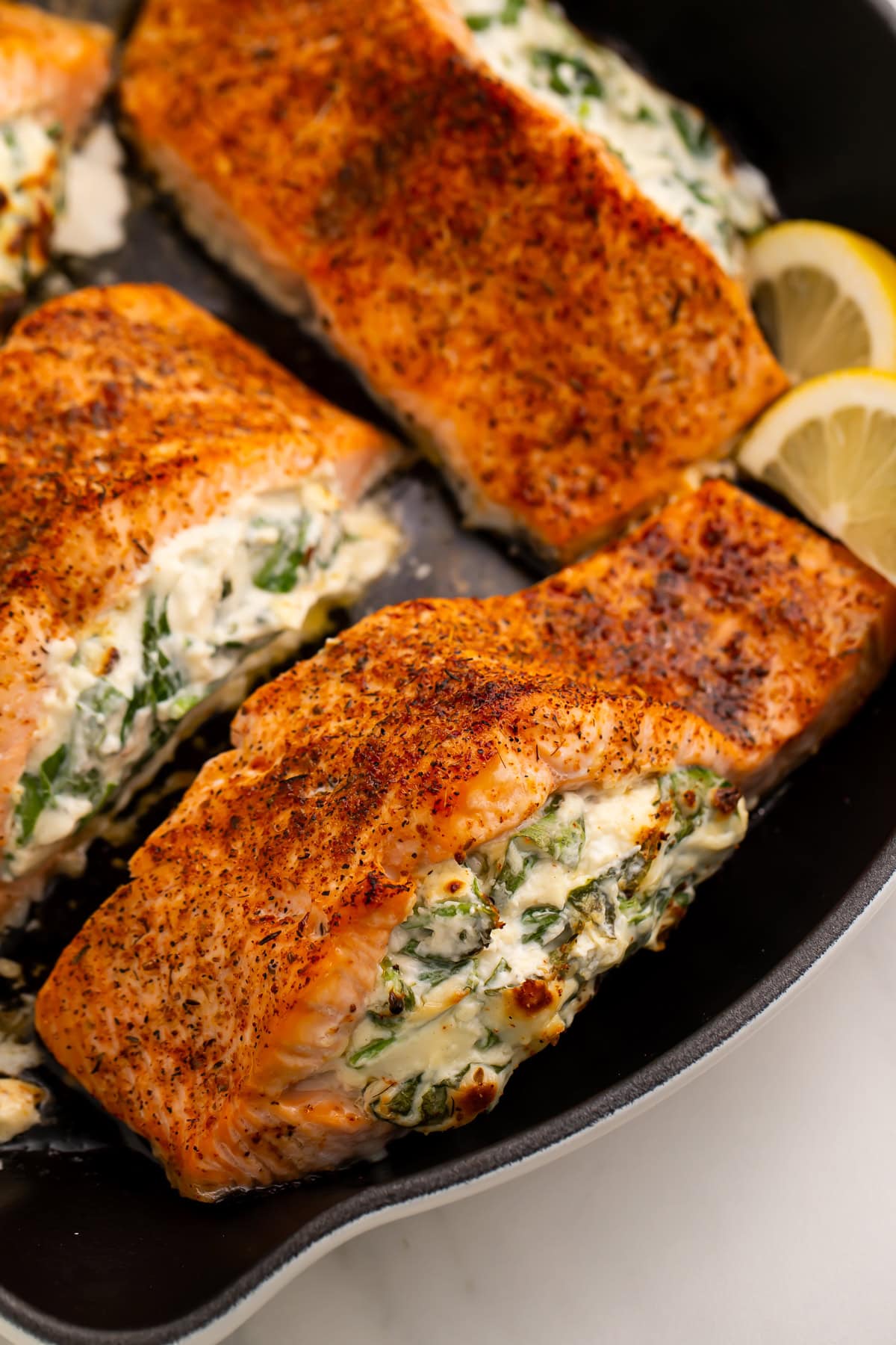 Broiled stuffed salmon fillets with creamy spinach filling in cast iron skillet