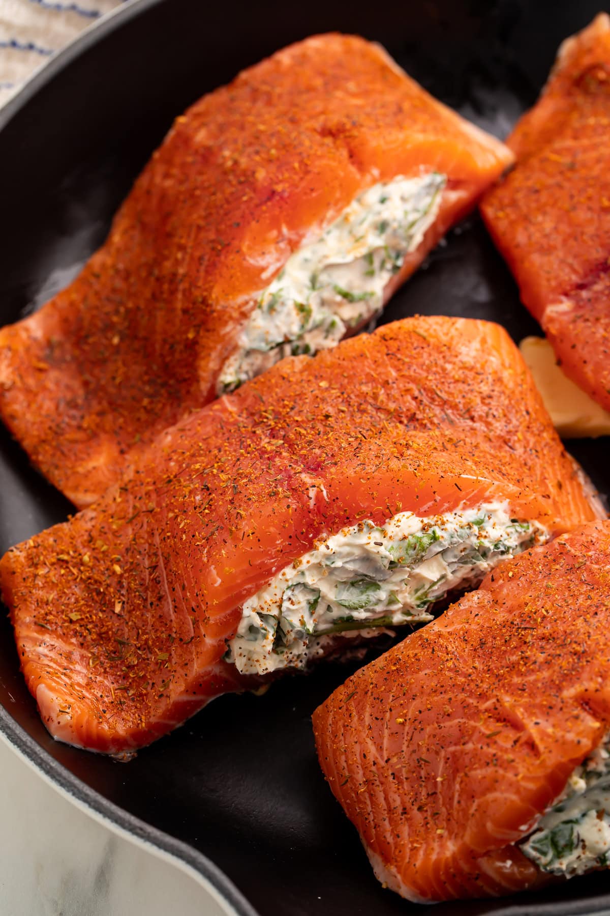 Raw salmon fillets with pockets cut and creamy filling visible
