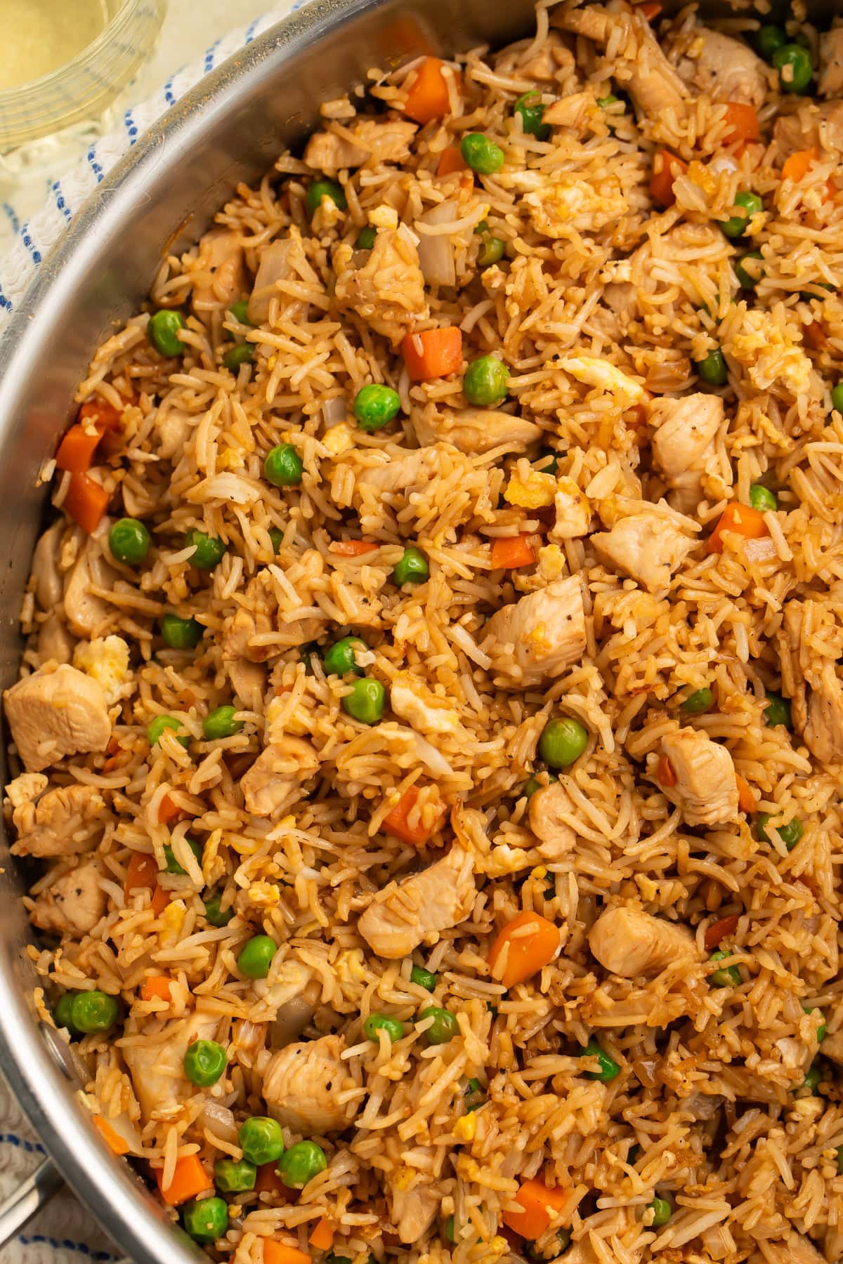 Garlic butter chicken fried rice cooking in a large stainless steel skillet with visible scrambled eggs