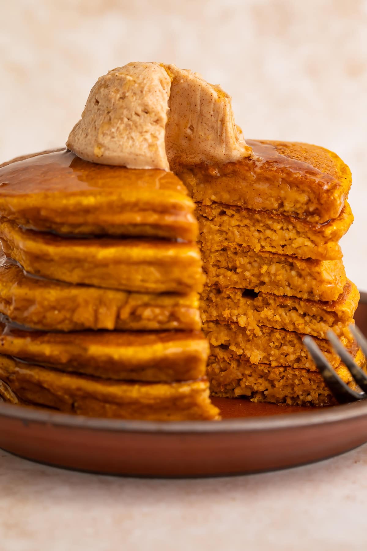 Cut pumpkin protein pancakes showing fluffy interior texture with cinnamon butter and fork