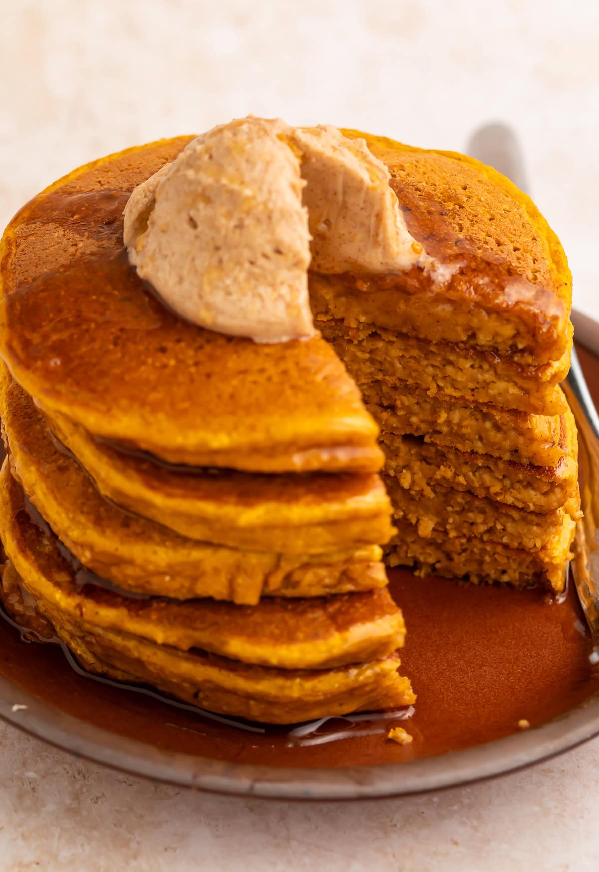 Sliced pumpkin protein pancakes showing cross-section with cinnamon butter on brown plate