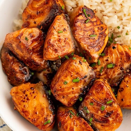 Hot honey salmon bites with caramelized glaze served over white rice in a white bowl