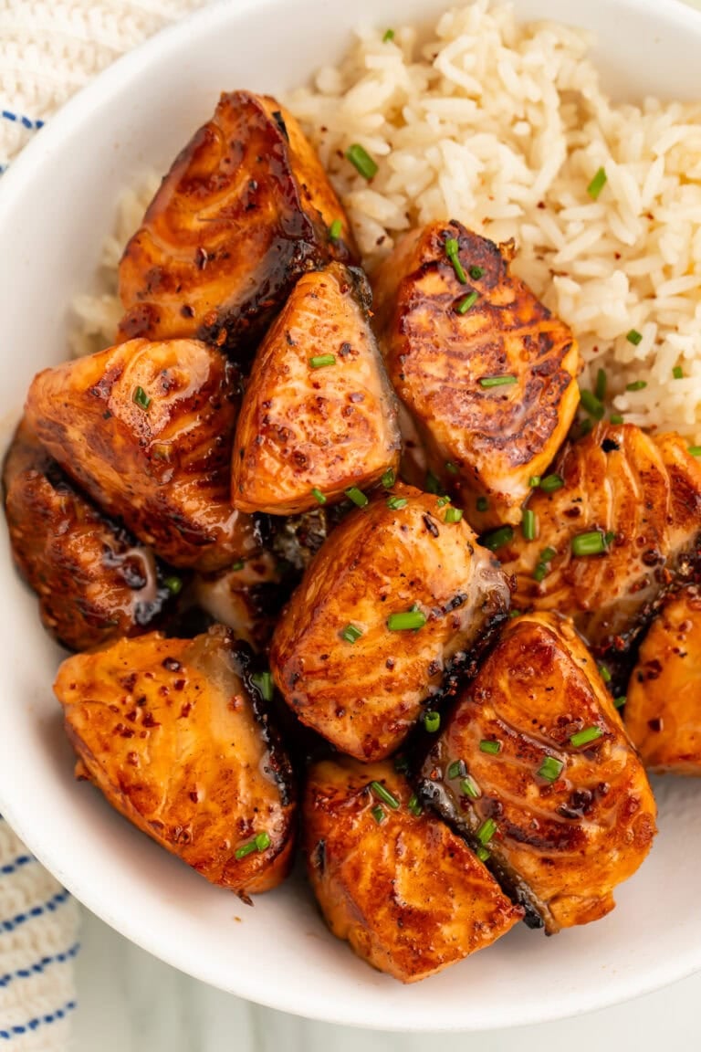Hot honey salmon bites with caramelized glaze served over white rice in a white bowl