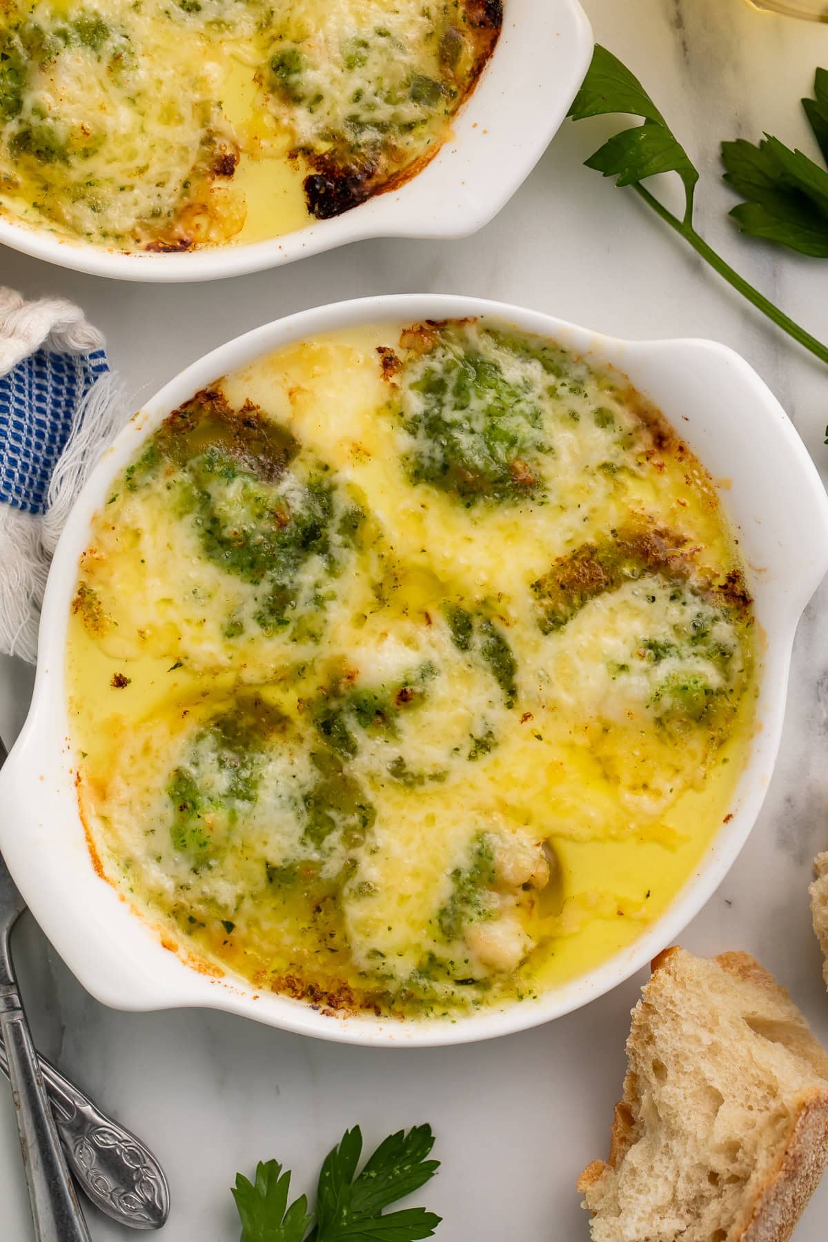 Lobster escargot in white ramekins with melted cheese and fresh parsley