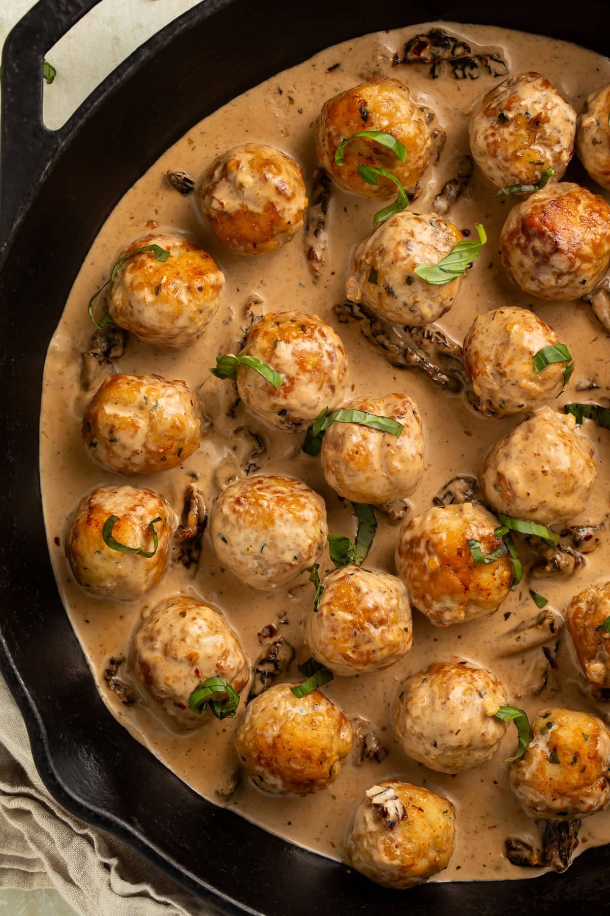 Overhead view of marry me chicken meatballs in cast iron skillet with creamy sun-dried tomato sauce