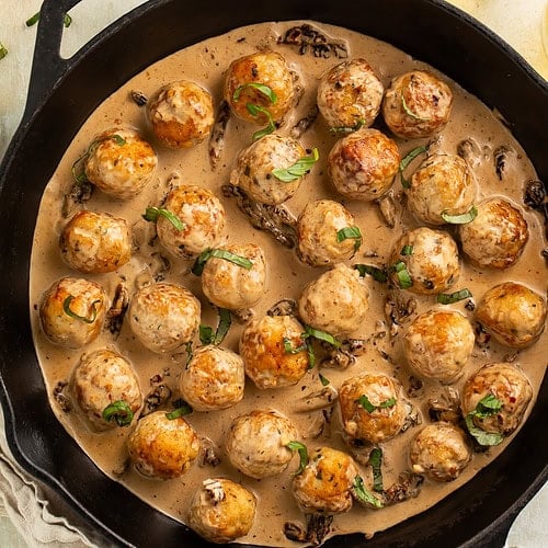 Golden brown chicken meatballs in creamy marry me sauce with sun-dried tomatoes in black cast iron skillet