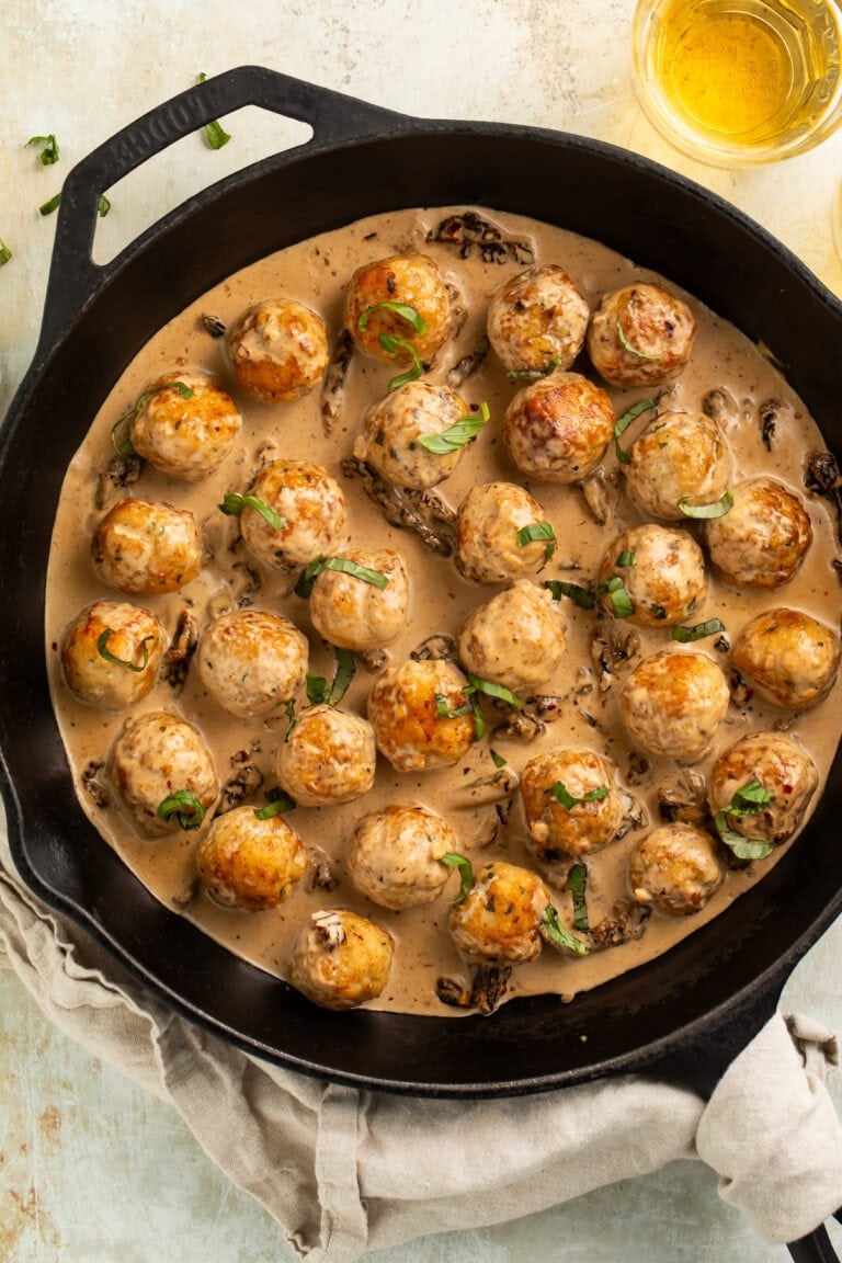 Golden brown chicken meatballs in creamy marry me sauce with sun-dried tomatoes in black cast iron skillet