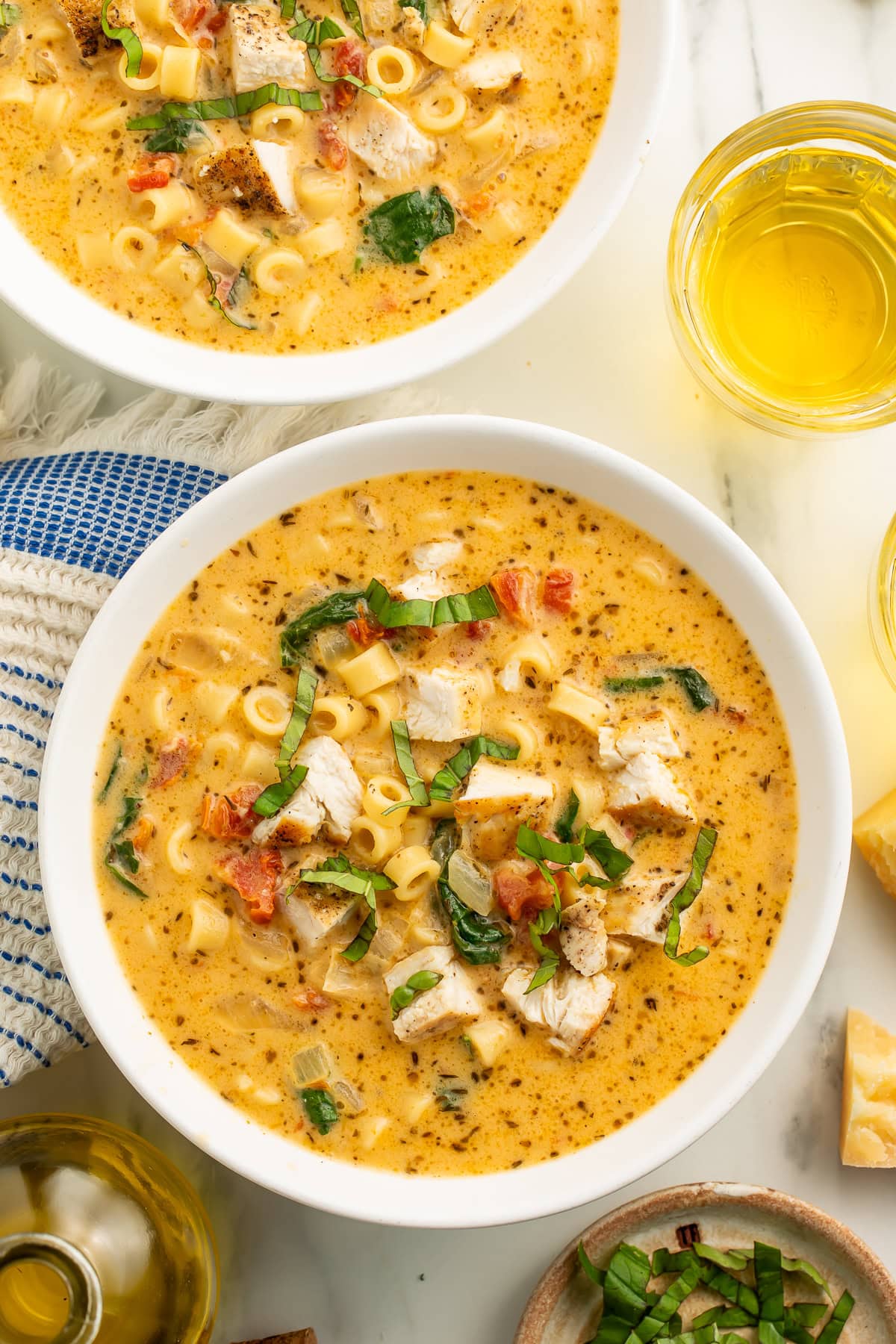 Close-up of Marry Me Chicken Soup showing creamy texture with visible pasta, seasoned chicken pieces, spinach, sun-dried tomatoes, and fresh basil