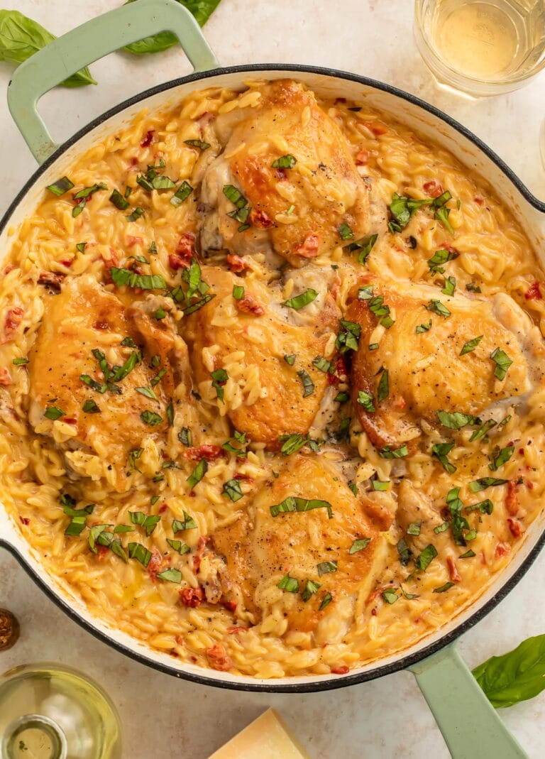 Marry me chicken and orzo skillet with golden chicken thighs in creamy sauce garnished with fresh basil