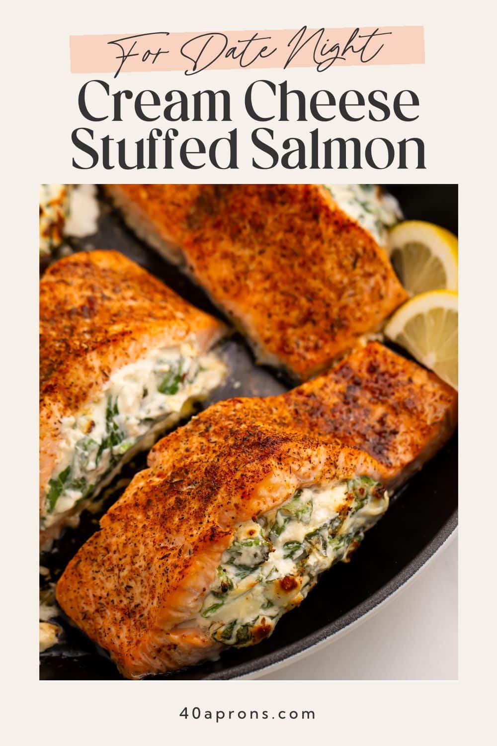 Seasoned stuffed salmon with cream cheese and spinach filling in black skillet with lemon slices
