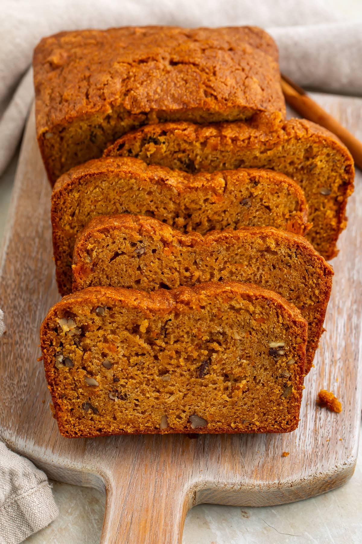 Sweet potato bread loaf partially sliced on cutting board with visible nuts and crumb texture 