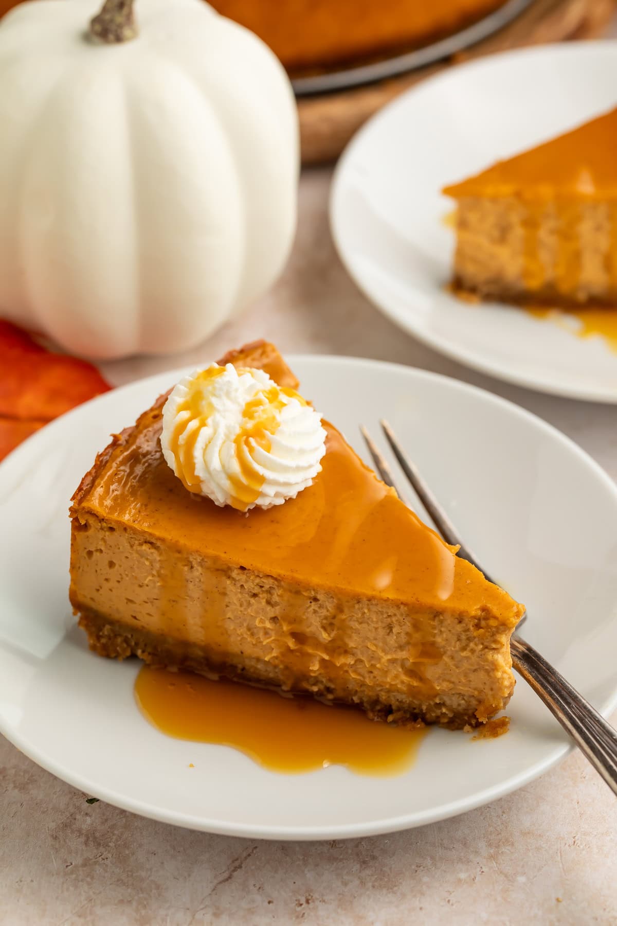 Single slice of pumpkin cheesecake on white plate with caramel sauce