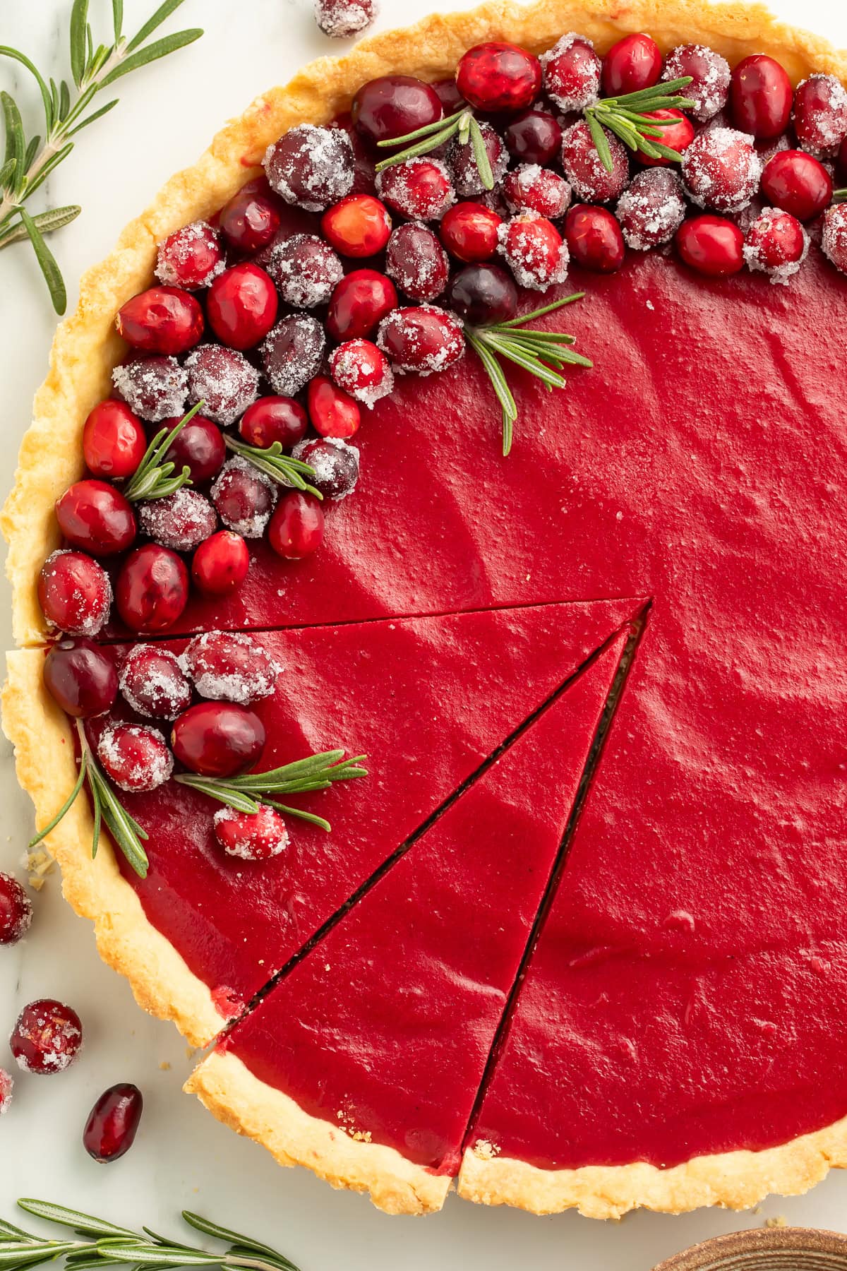 Overhead view of cranberry tart with two slices cut, showing smooth red filling and flaky crust