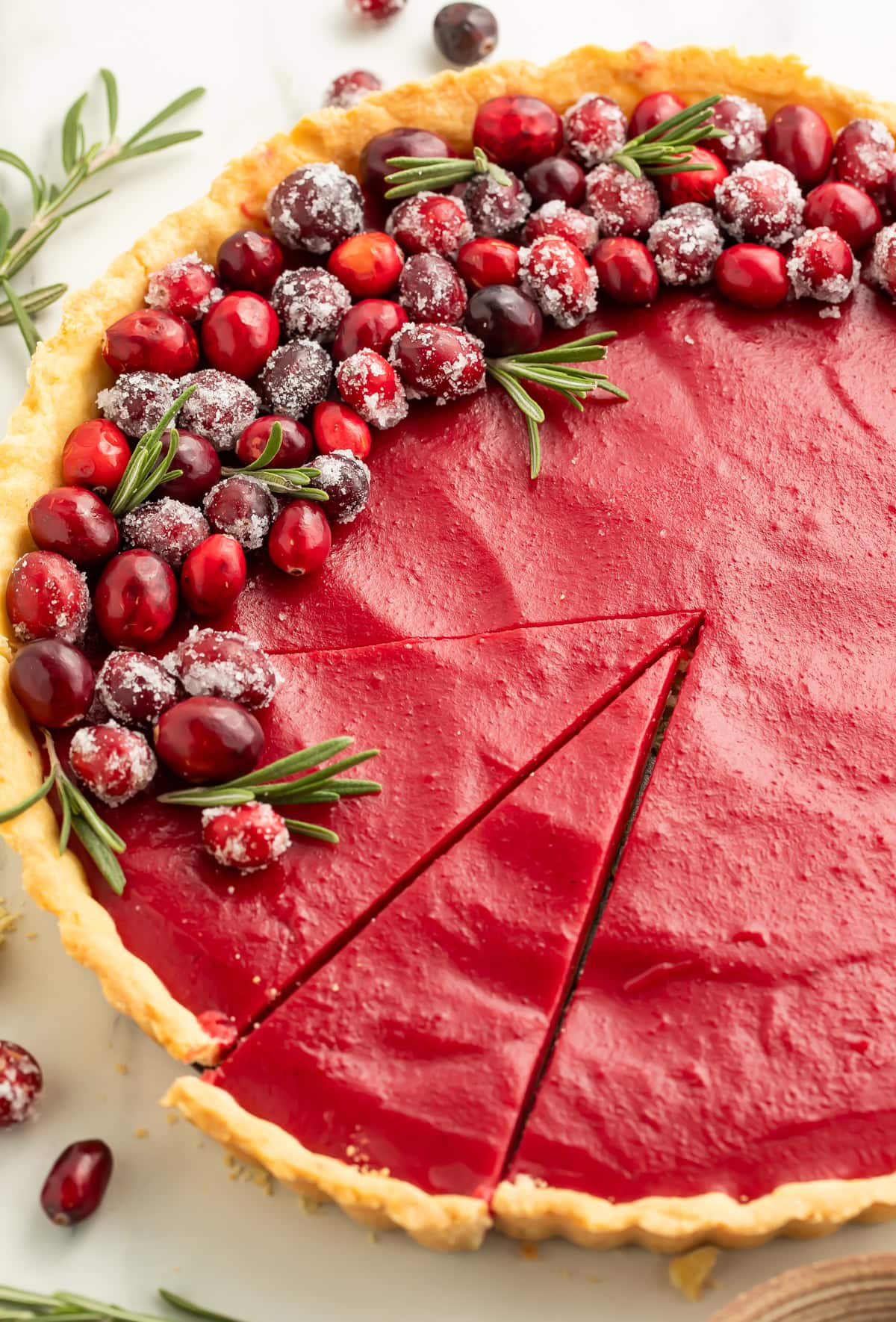 Whole cranberry tart with sugared cranberry garnish and serving slices marked on smooth red filling