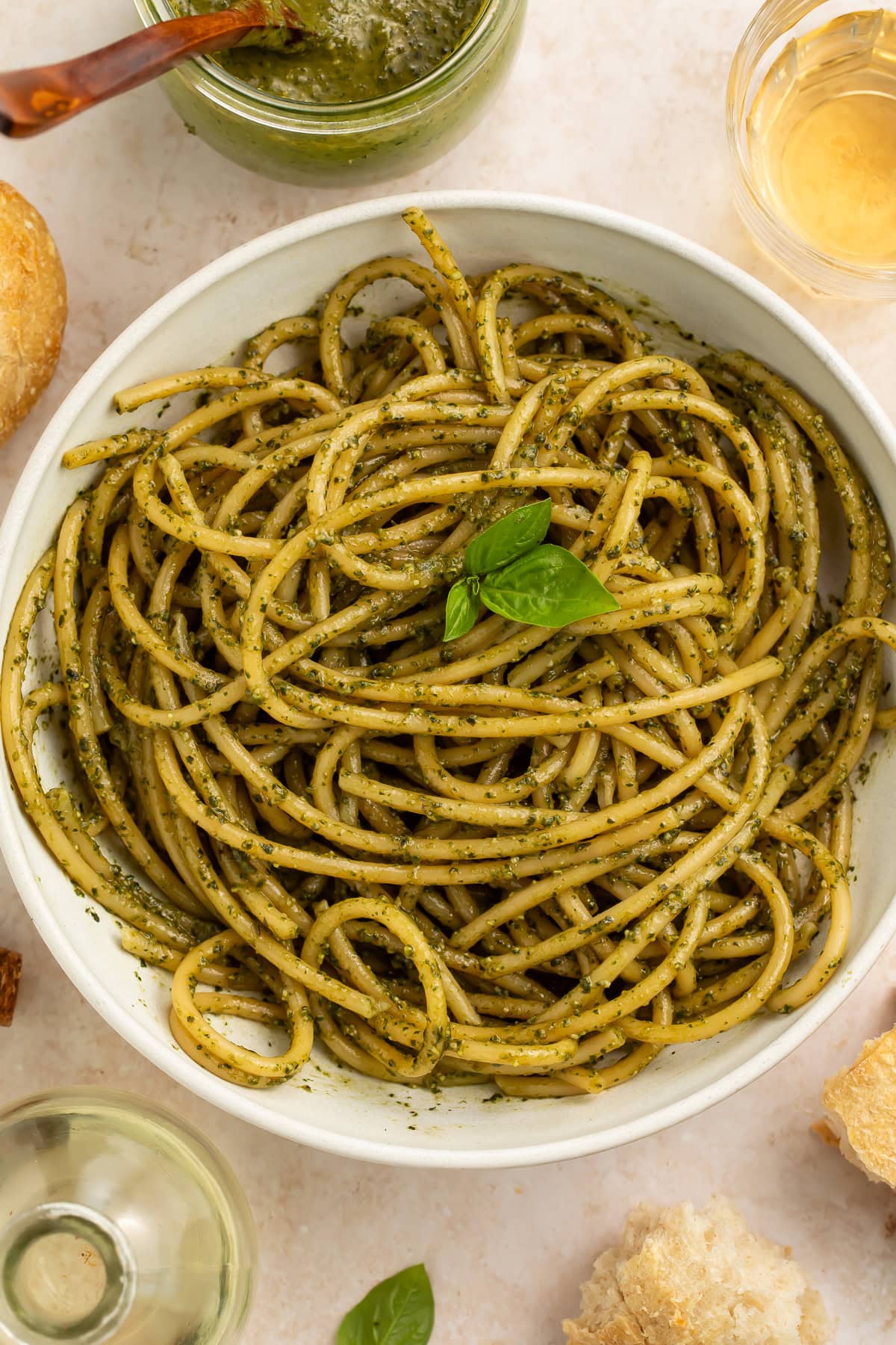 Spaghetti tossed with creamy pesto sauce in white bowl with basil garnish