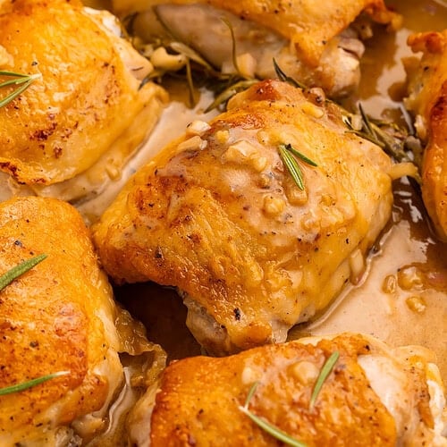 Maple dijon chicken thighs with crispy golden skin in white ceramic skillet