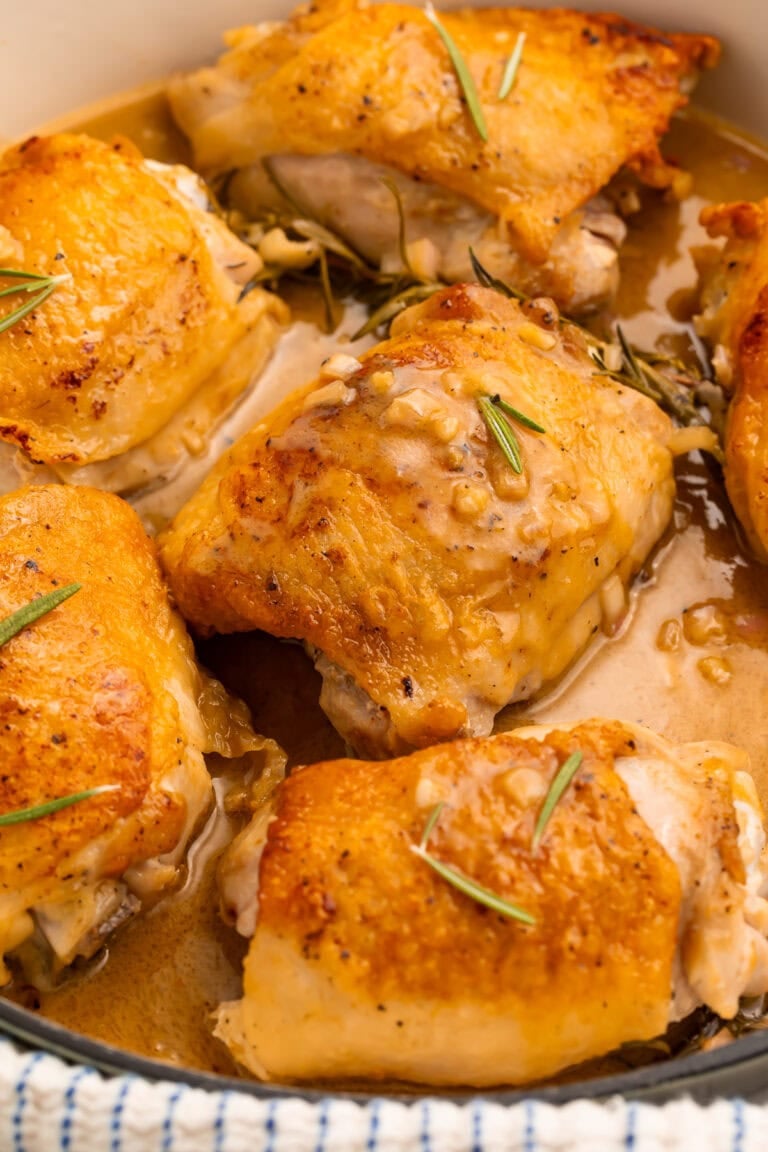 Maple dijon chicken thighs with crispy golden skin in white ceramic skillet