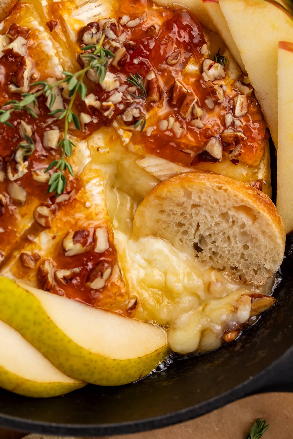 Close-up of melted brie cheese oozing out with bread slice and honey drizzle