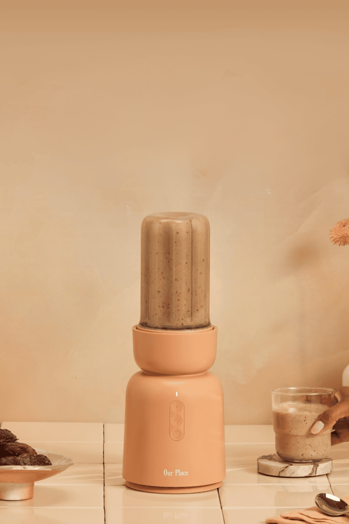 Our Place personal blender in coral color blending smoothie on countertop