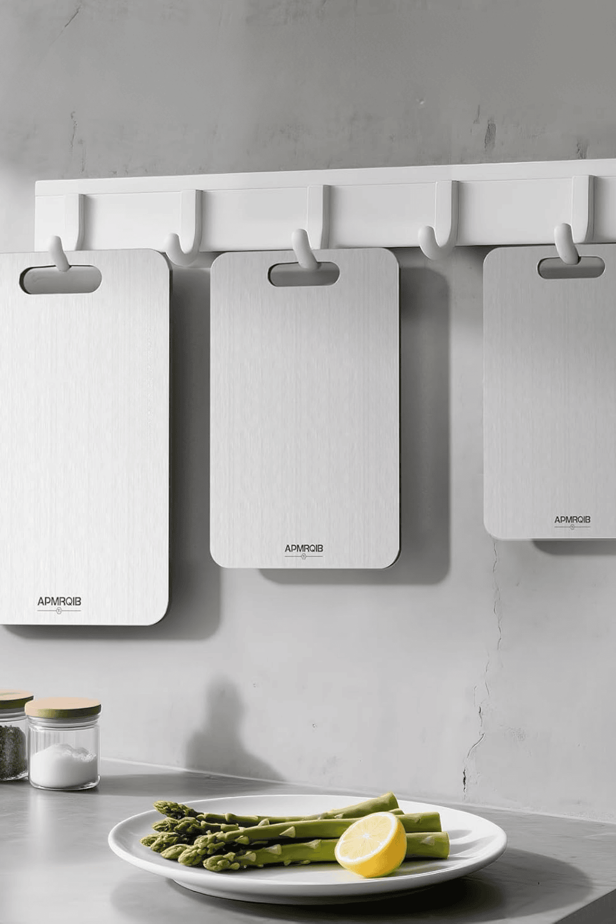 Three white titanium cutting boards hanging on wall hooks above asparagus plate