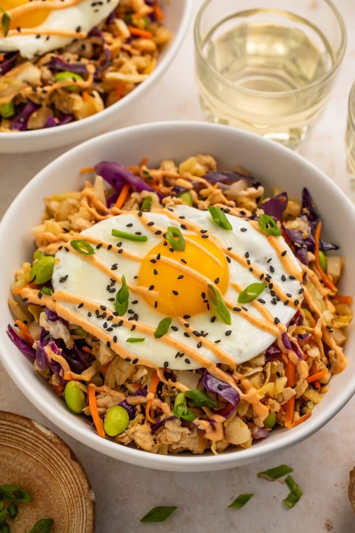 High protein egg roll in a bowl topped with a fried egg and drizzled with creamy chili sauce