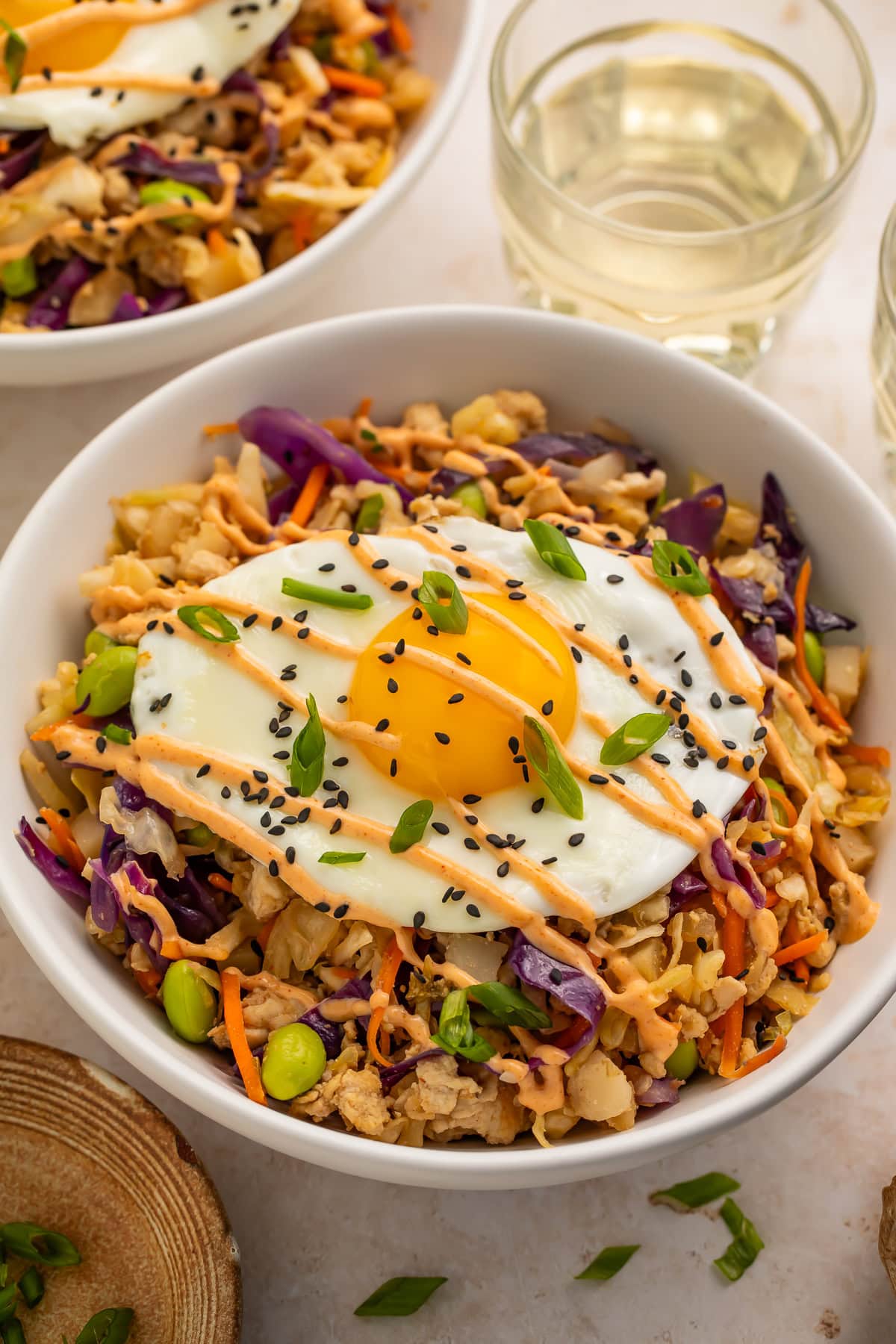 High protein egg roll in a bowl topped with a fried egg and drizzled with creamy chili sauce