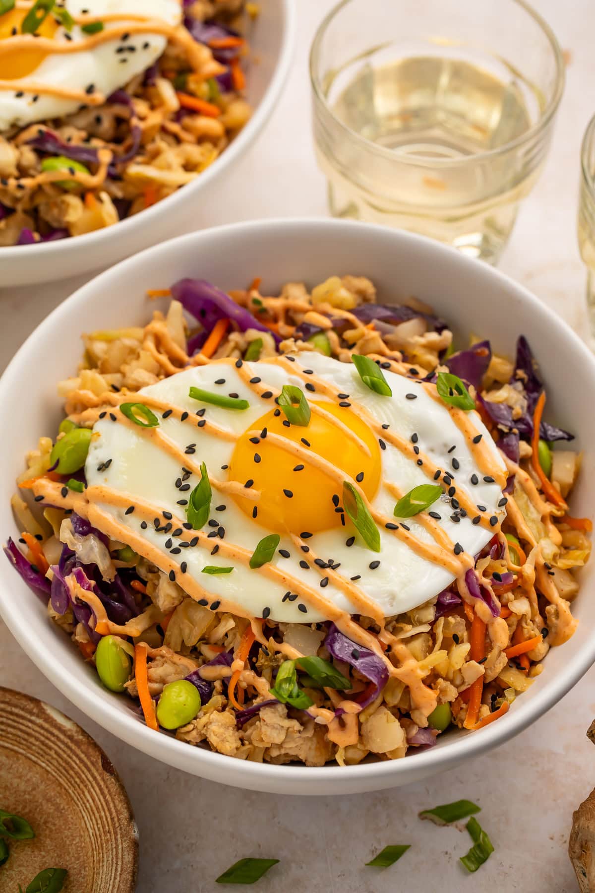 Overhead view of high protein pork egg roll bowl with fried egg, sesame seeds, and green onion garnish