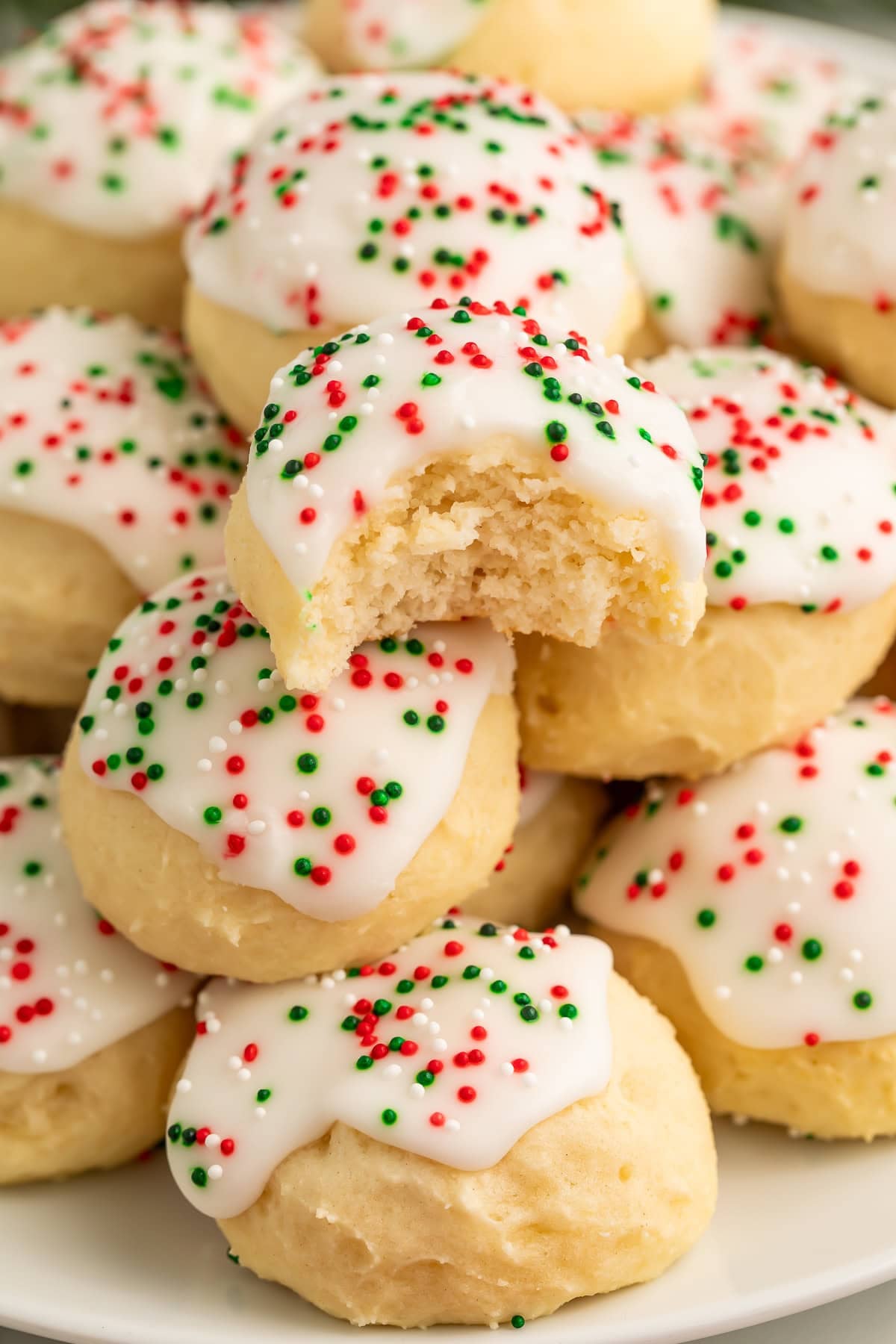 Italian ricotta cookie broken in half showing soft cake-like interior texture with white glaze and colorful sprinkles