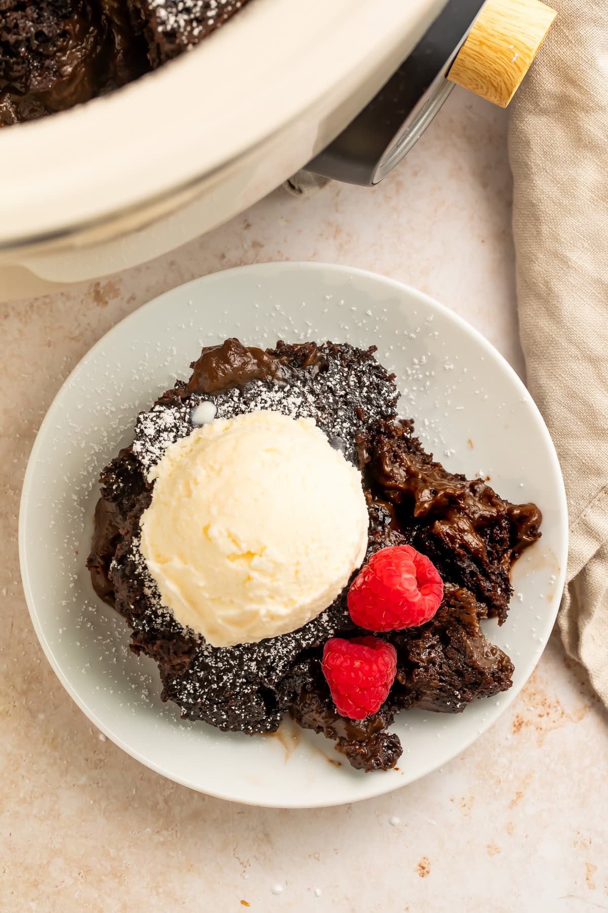 Slow cooker lava cake with vanilla ice cream and raspberries dusted with powdered sugar