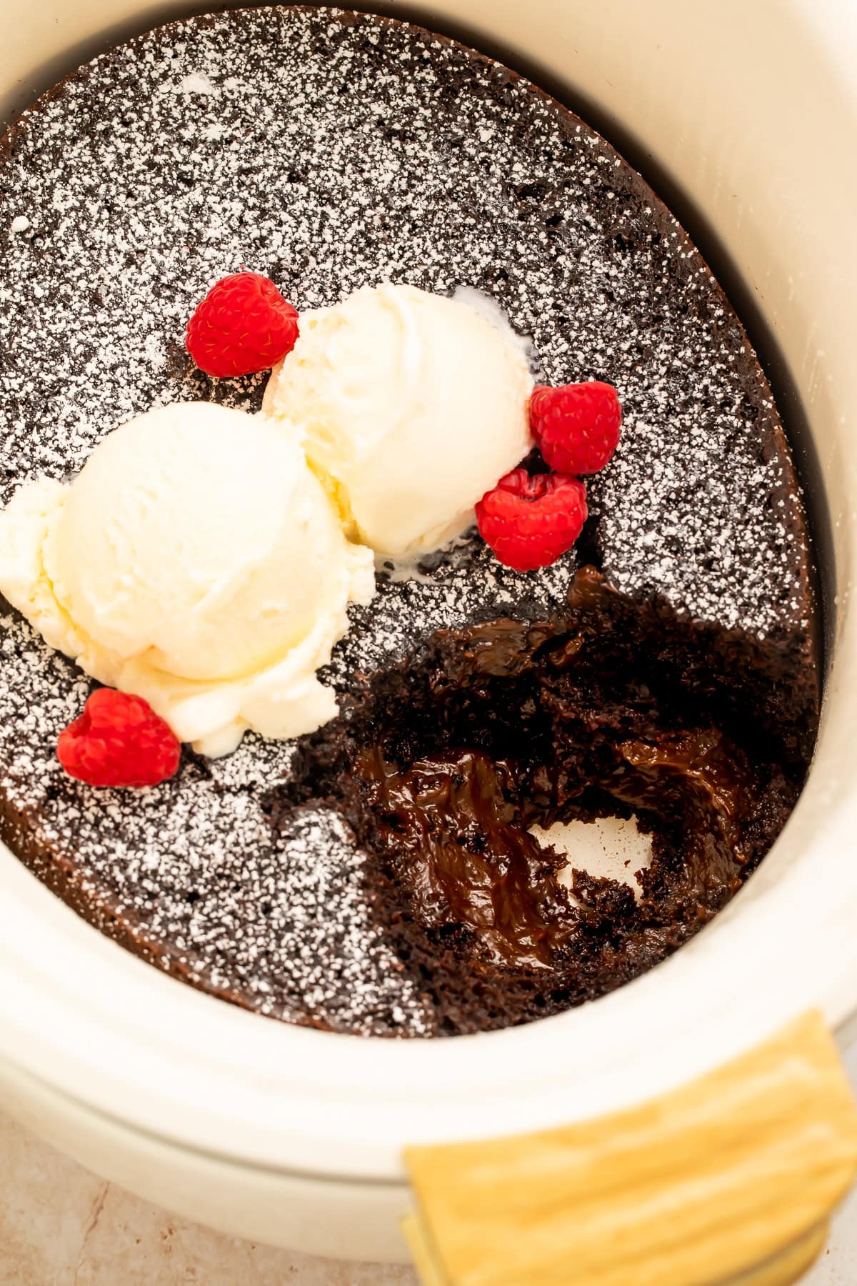 Overhead view of molten lava cake in slow cooker with ice cream and raspberries