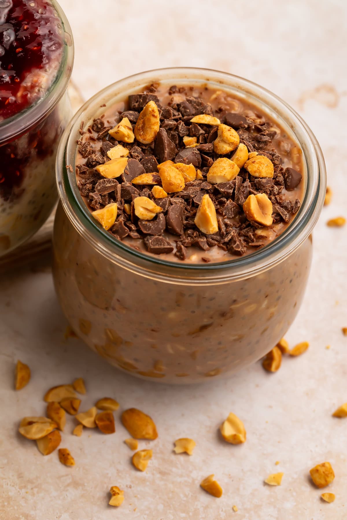 Close up of chocolate peanut butter overnight oats topped with chocolate shavings and roasted peanuts in jar