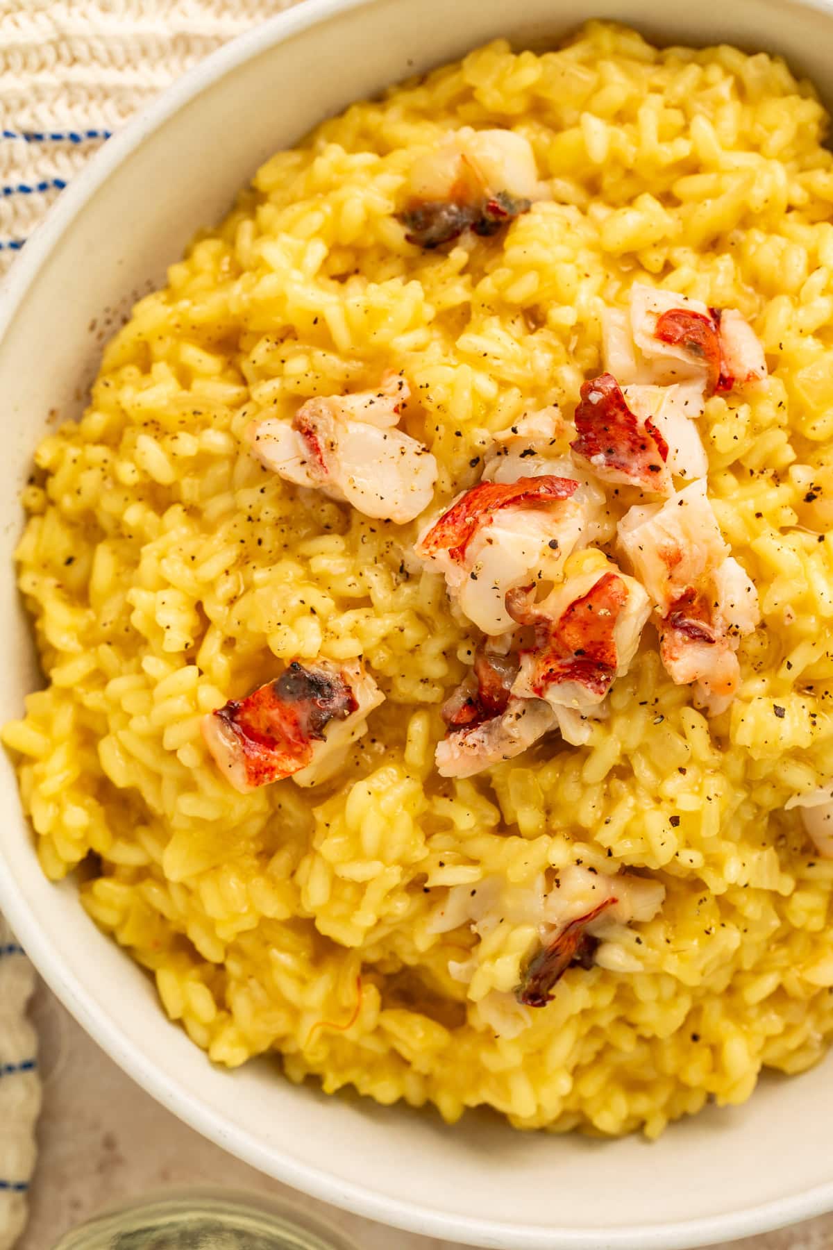 Close-up of saffron risotto with chunks of butter-poached lobster meat and black pepper seasoning