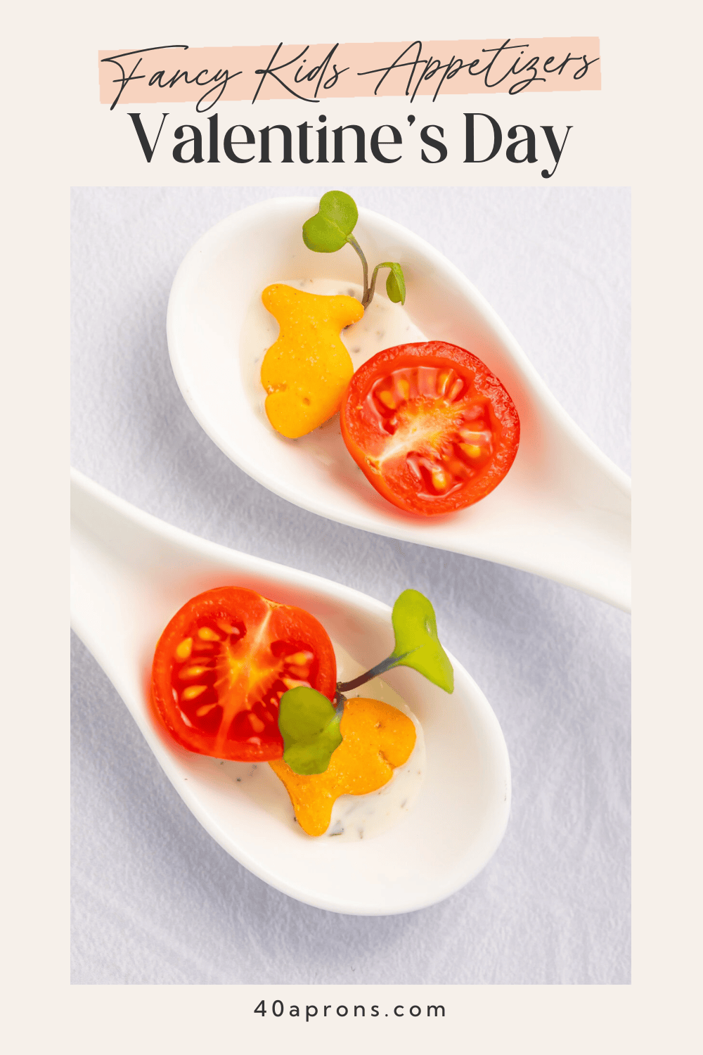 Pinterest pin for fancy kids Valentine's appetizers showing Goldfish crackers on white tasting spoons with cherry tomato, cucumber, and micro-greens