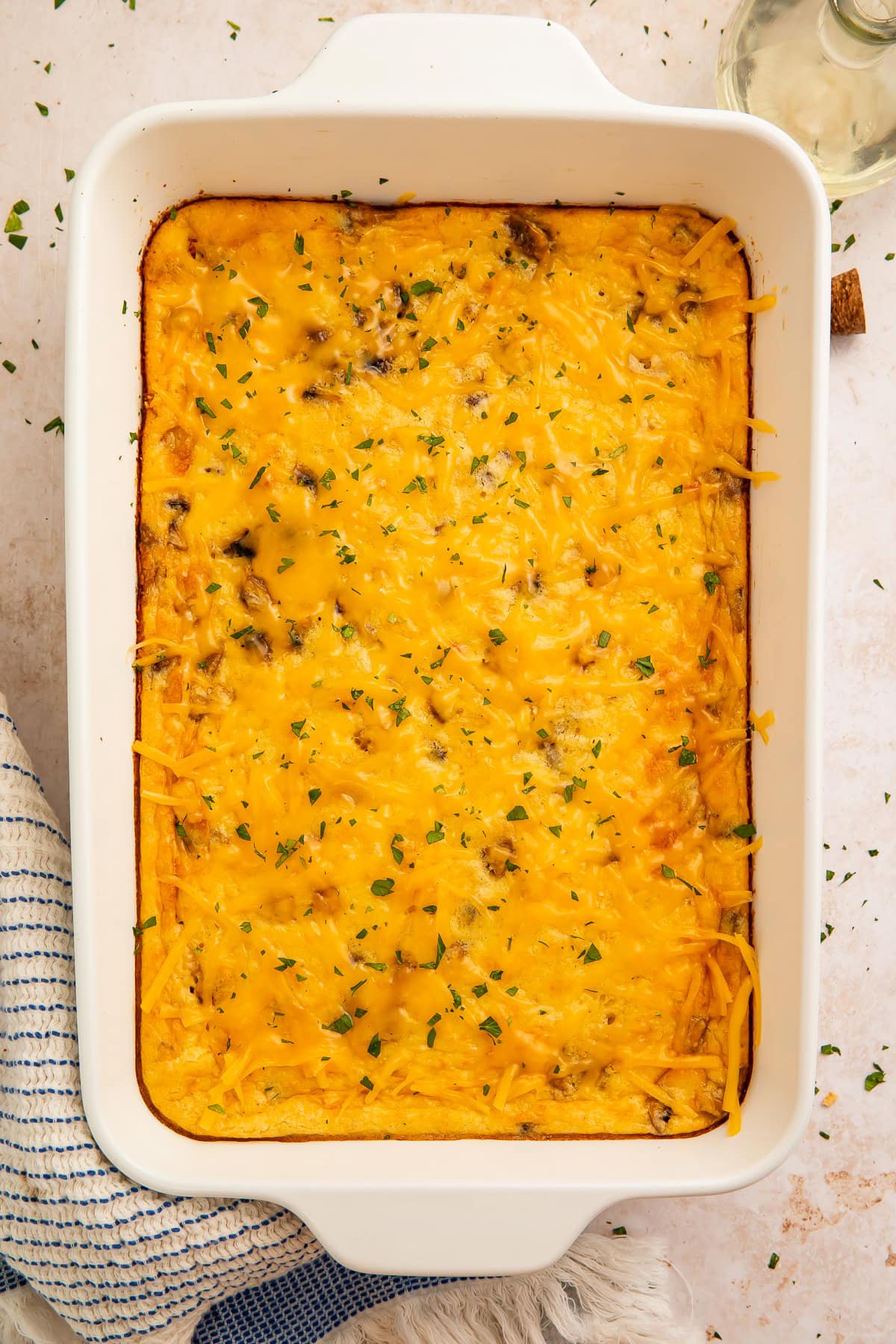 Overhead view of a full cottage cheese egg bake in a white rectangular casserole dish garnished with parsley.