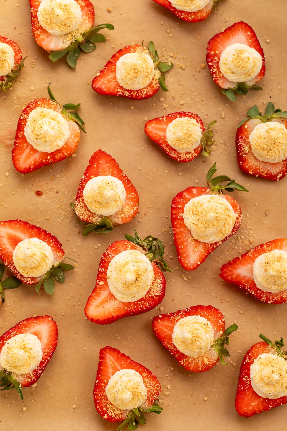 Overhead view of deviled strawberries with cream cheese filling arranged on brown parchment paper