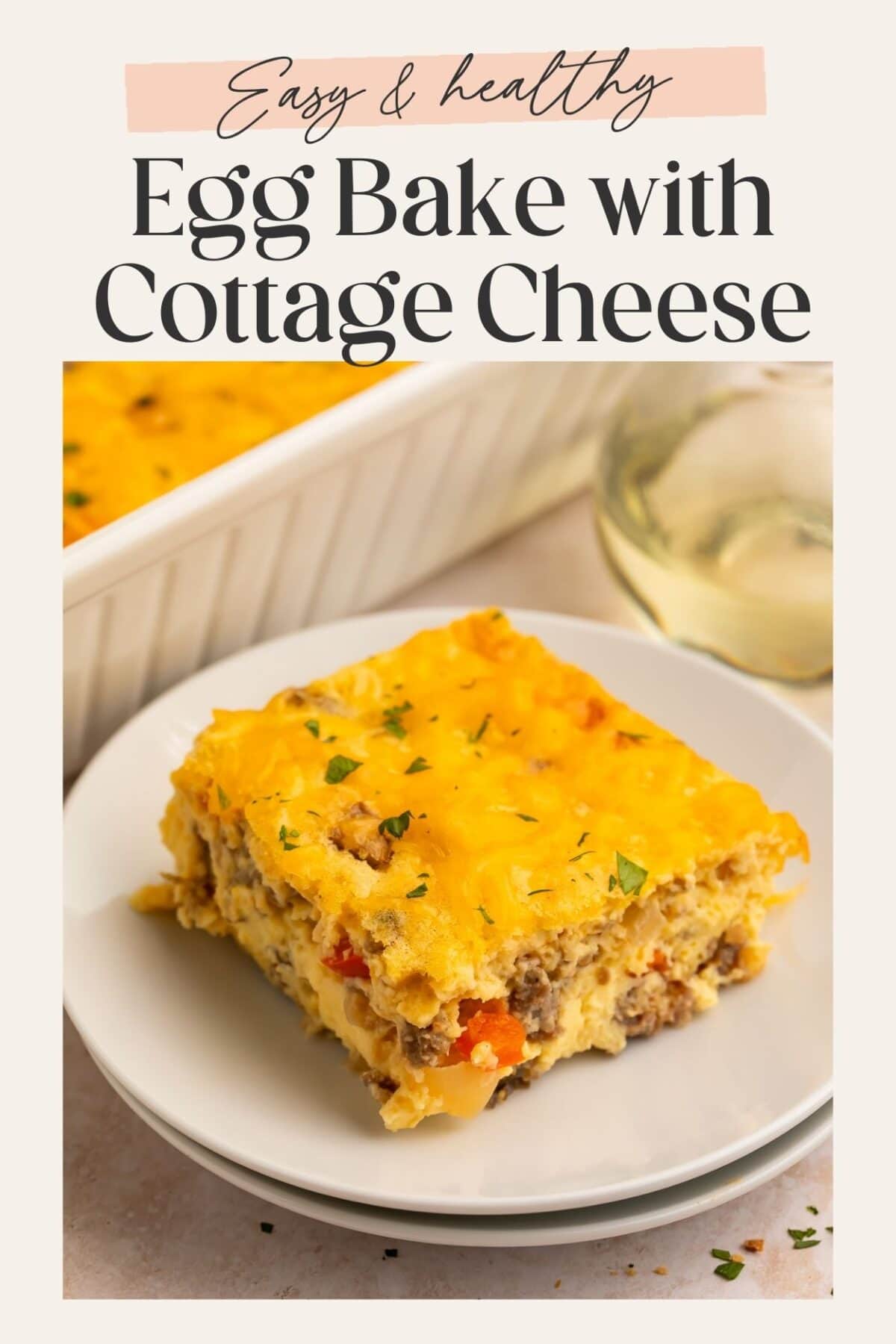 A cheesy slice of egg bake with cottage cheese on a white plate with a casserole dish in the background