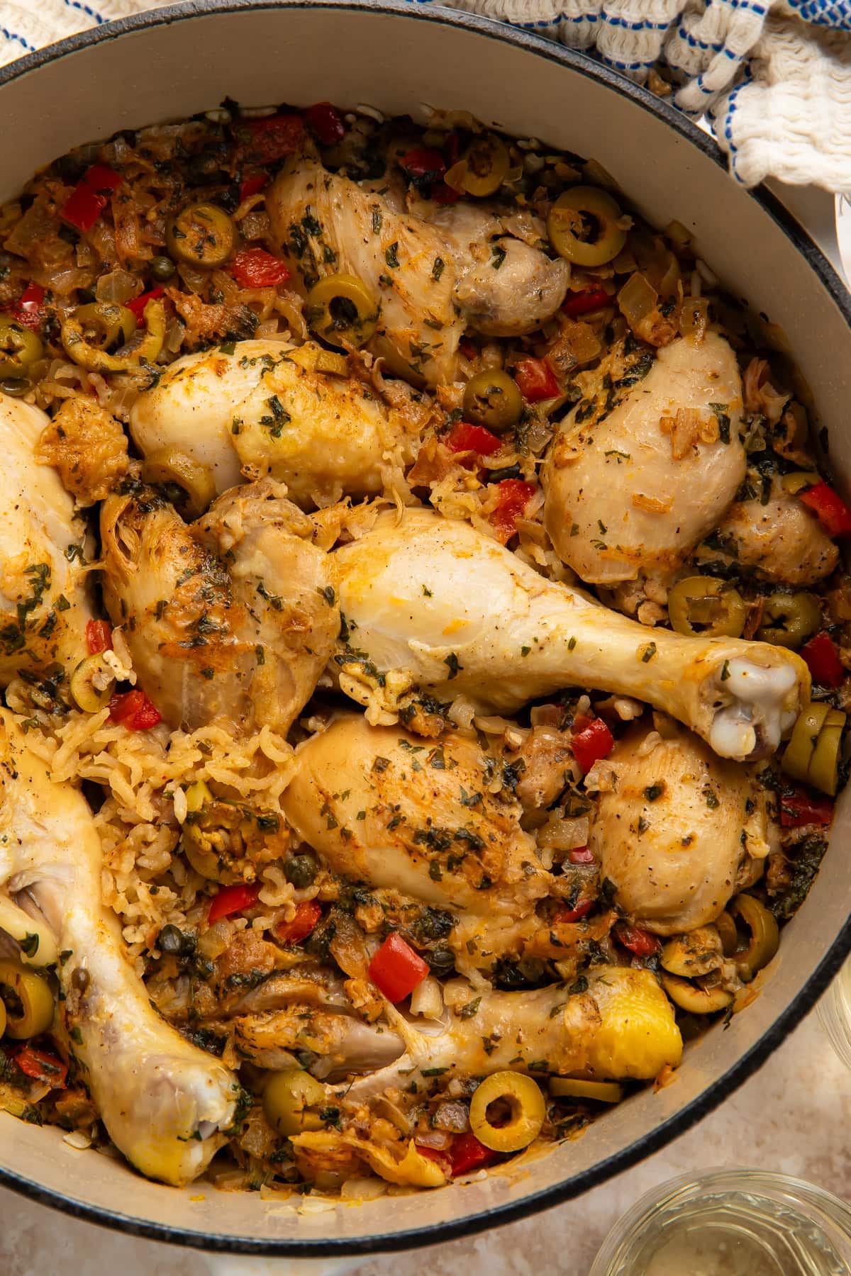One pot Spanish chicken and rice with drumsticks, green olives, red pepper, and herbs in a Dutch oven
