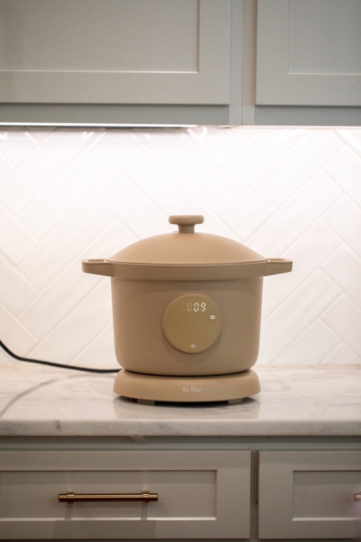 Our Place Dream Cooker in beige displayed on a white marble kitchen countertop