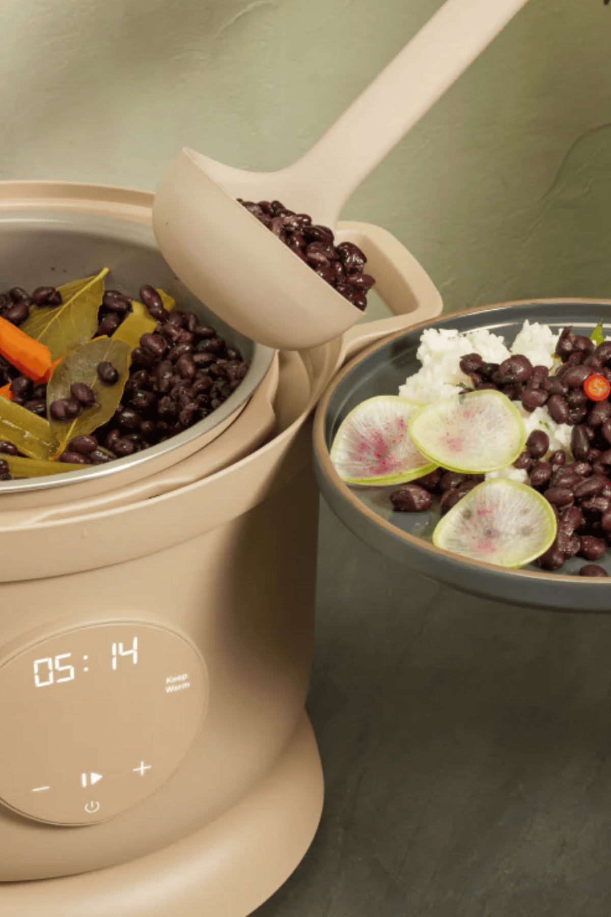 Our Place Dream Cooker open with black beans inside next to a finished bowl of beans and rice