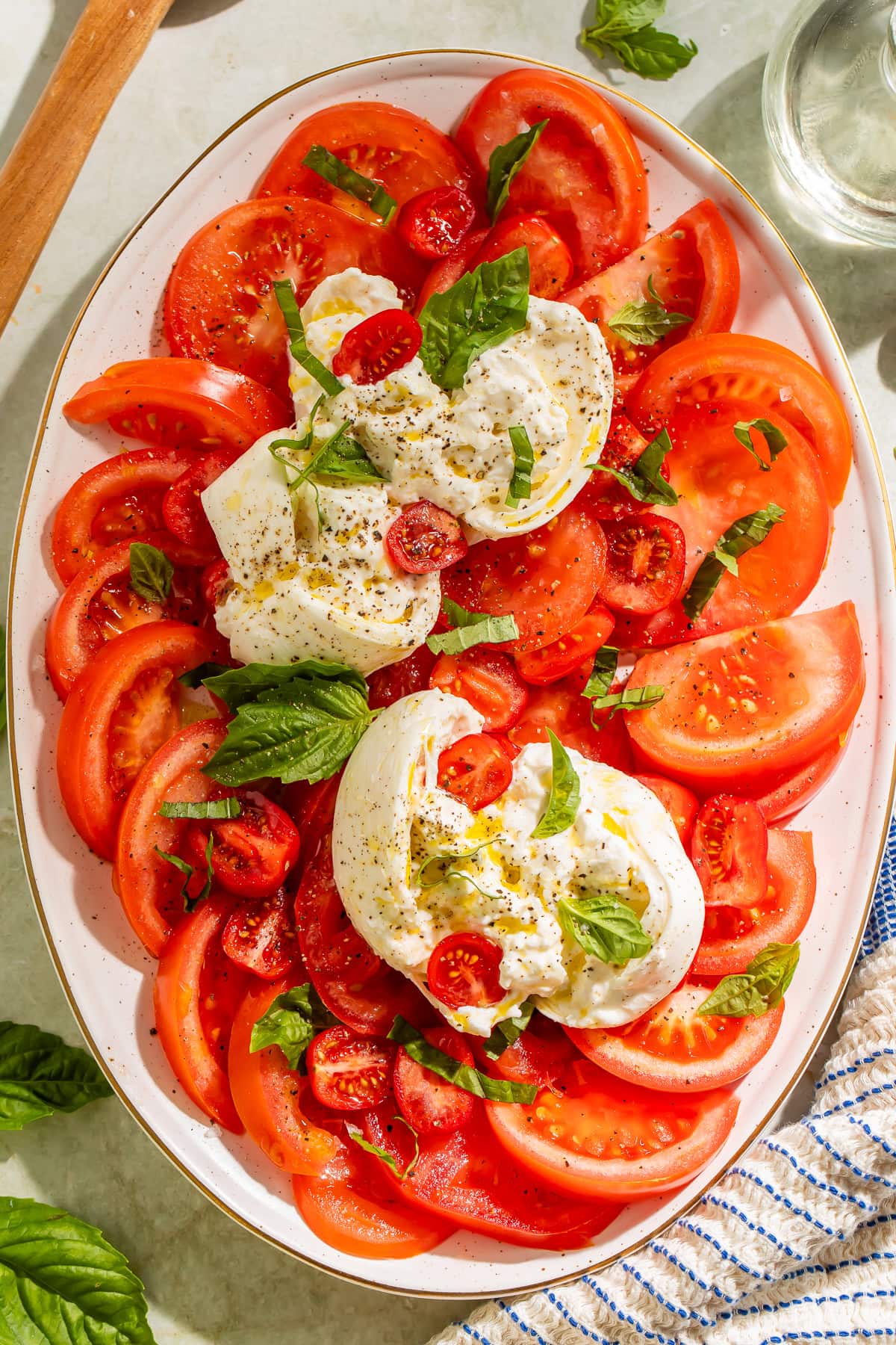 Overhead view of full burrata caprese salad platter with tomatoes, burrata, and chiffonaded basil