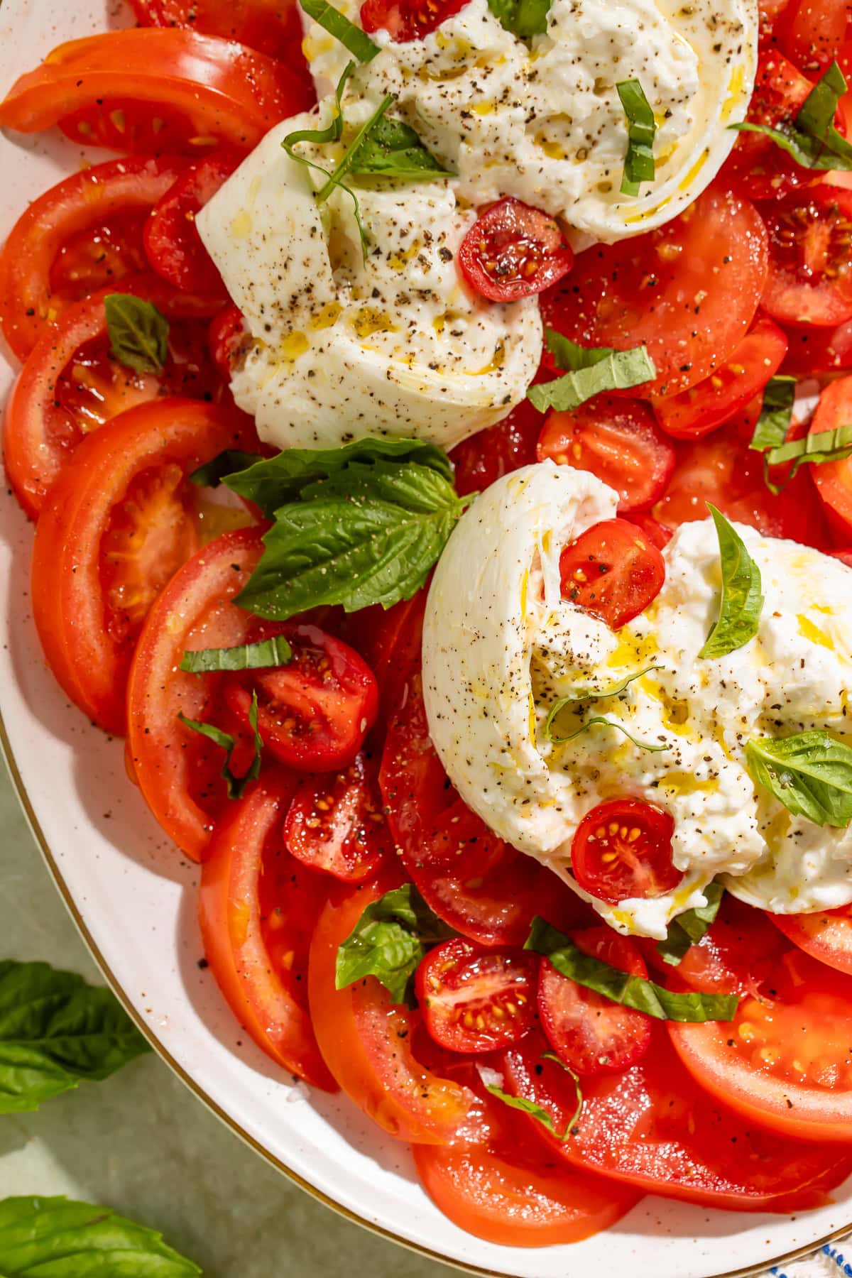 Close-up overhead shot of burrata caprese salad with juicy tomatoes, basil, and creamy burrata