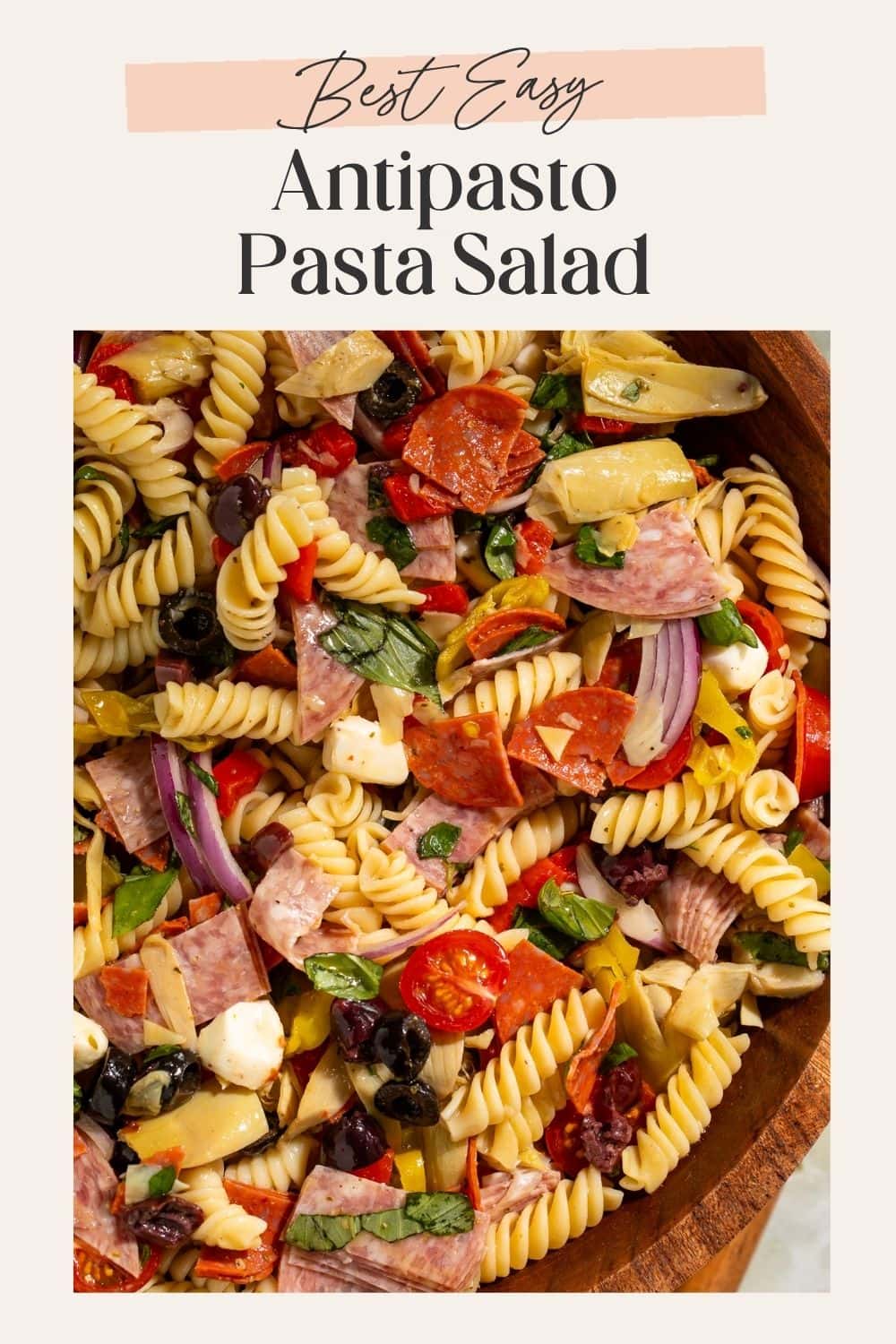 Close up of a bowl of antipasto pasta salad. There is a frame on the image with a Pinterest-optimised text overlay.
