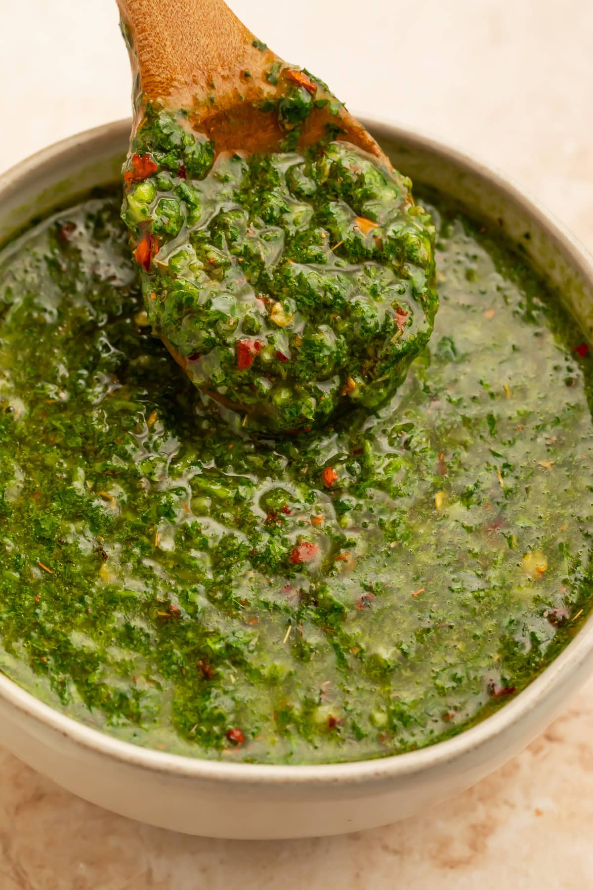 Close up of chimichurri sauce being spooned out of a bowl.