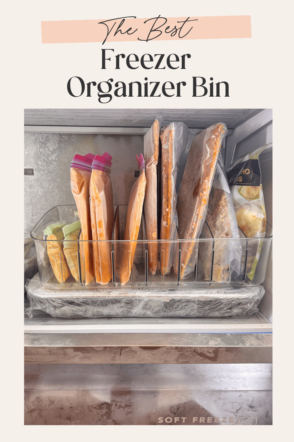 A wide clear freezer organizer bin filled with multiple upright frozen meal bags on a freezer shelf