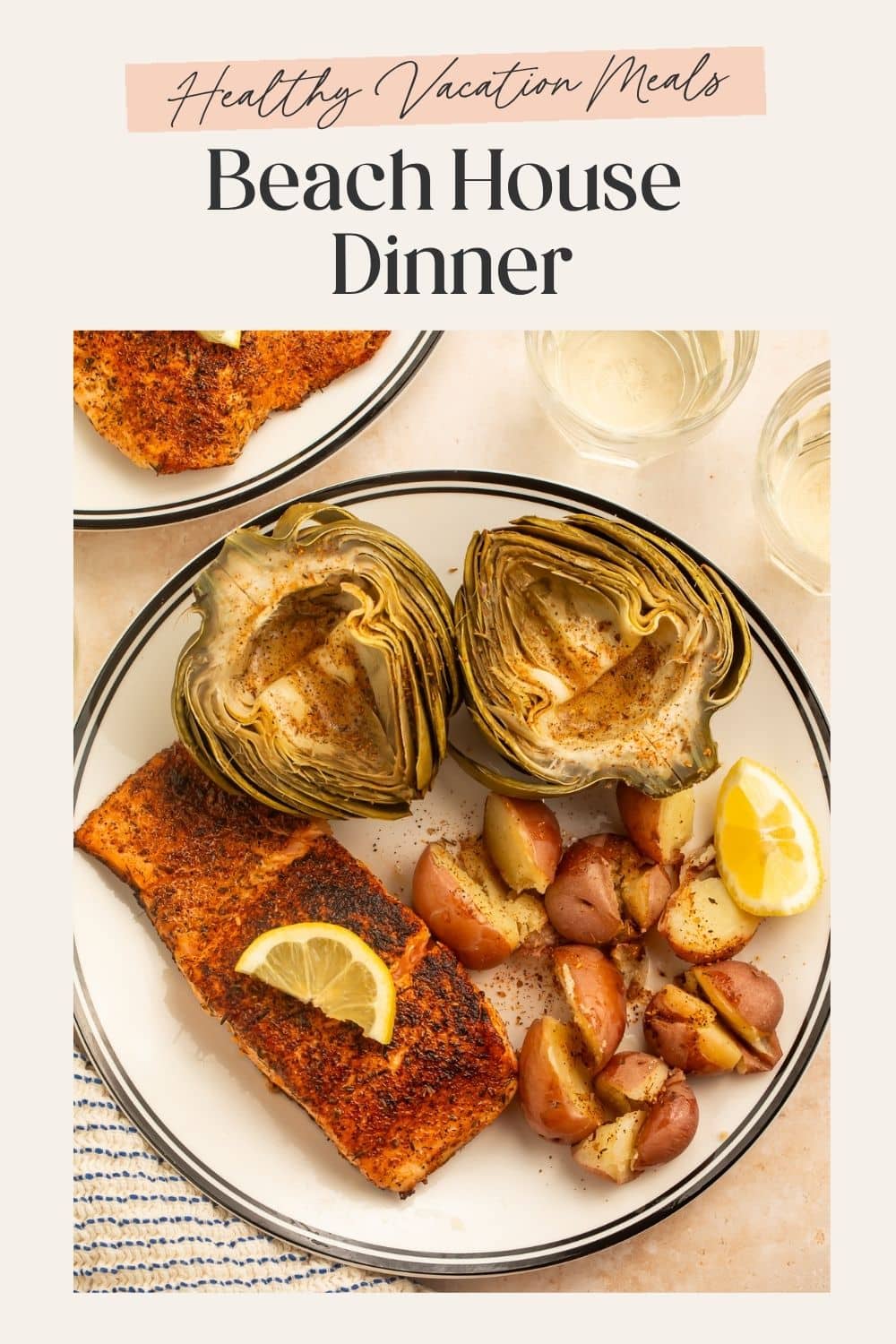 Beach house dinner idea plate of salmon, steamed halved artichoke, steamed red potatoes and lemon slices, with a frame on the image hosting Pinterest-optimised text.