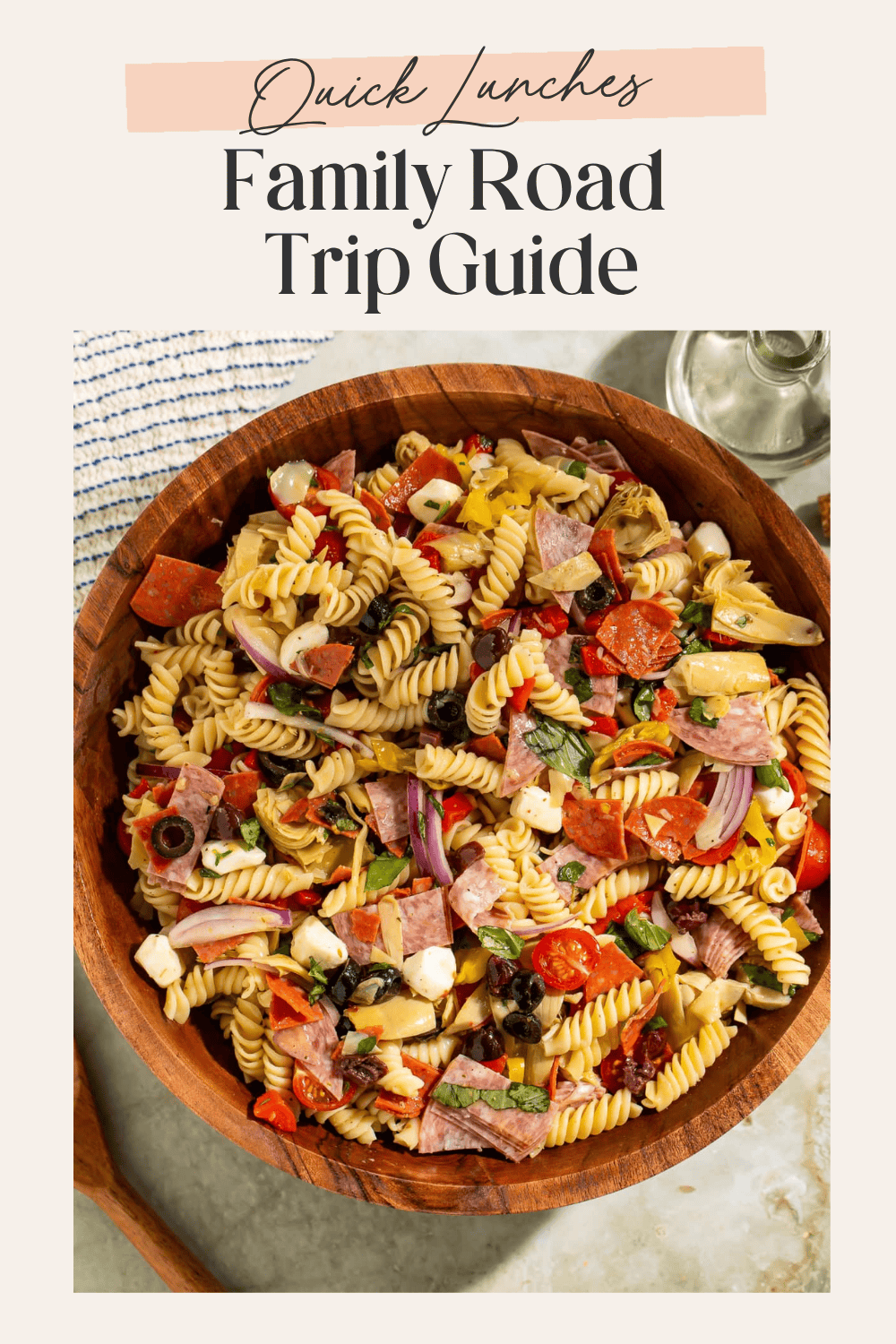 Large wooden bowl filled with Italian pasta salad with salami, pepperoni, olives, and mozzarella